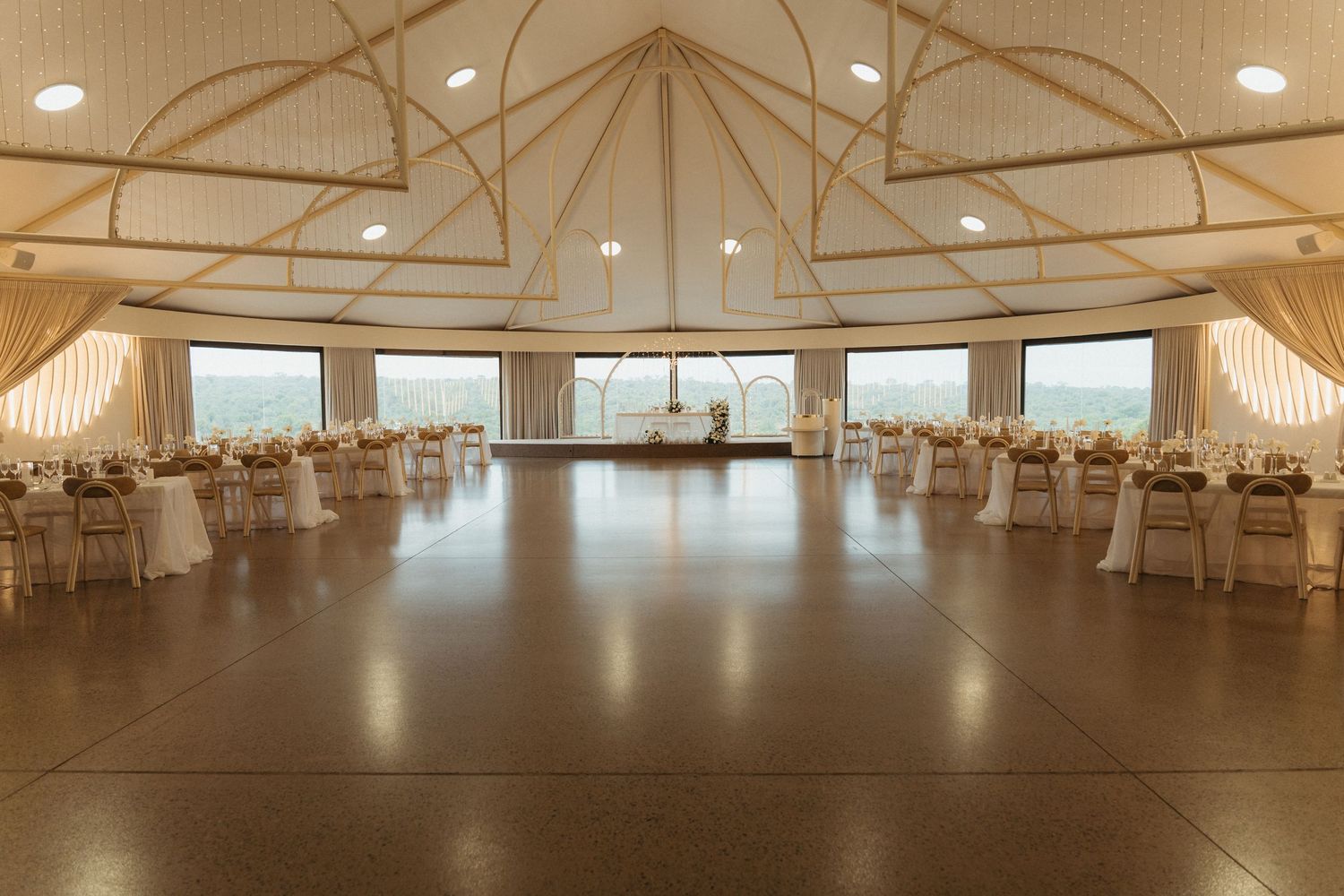 Elegant Bona Bona wedding reception hall with vaulted ceiling, draped walls, round tables and panoramic views.