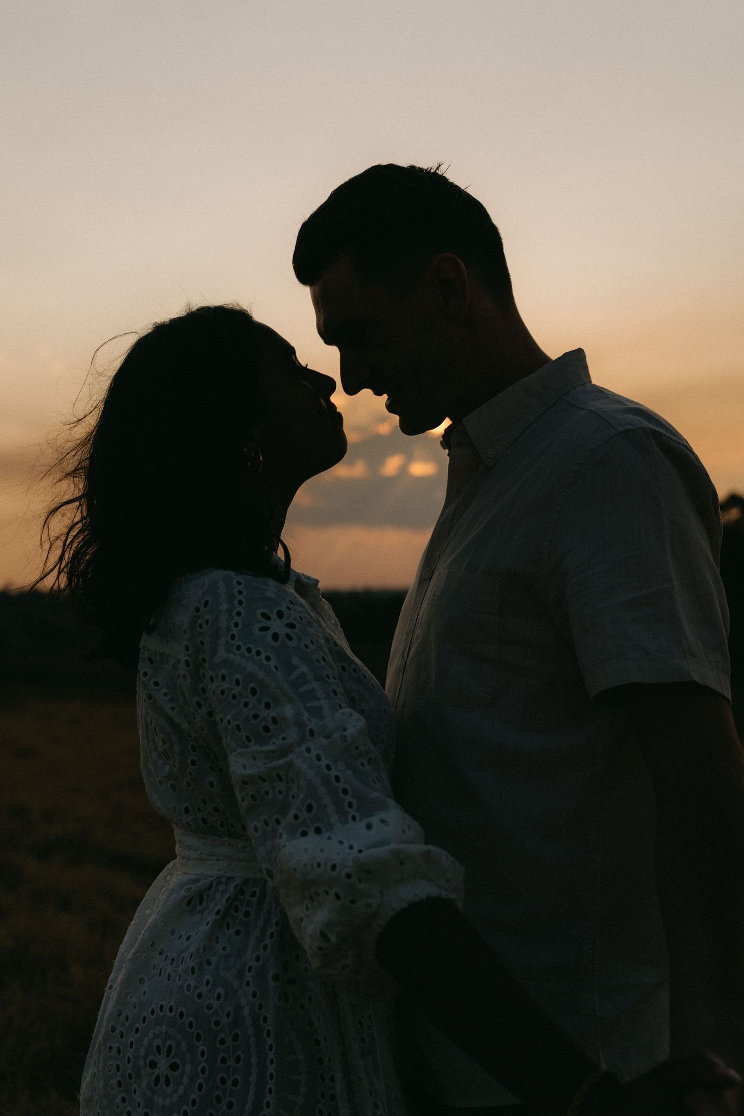 Romantic silhouette of a couple leaning in for a kiss against a warm golden Johannesburg sunset.