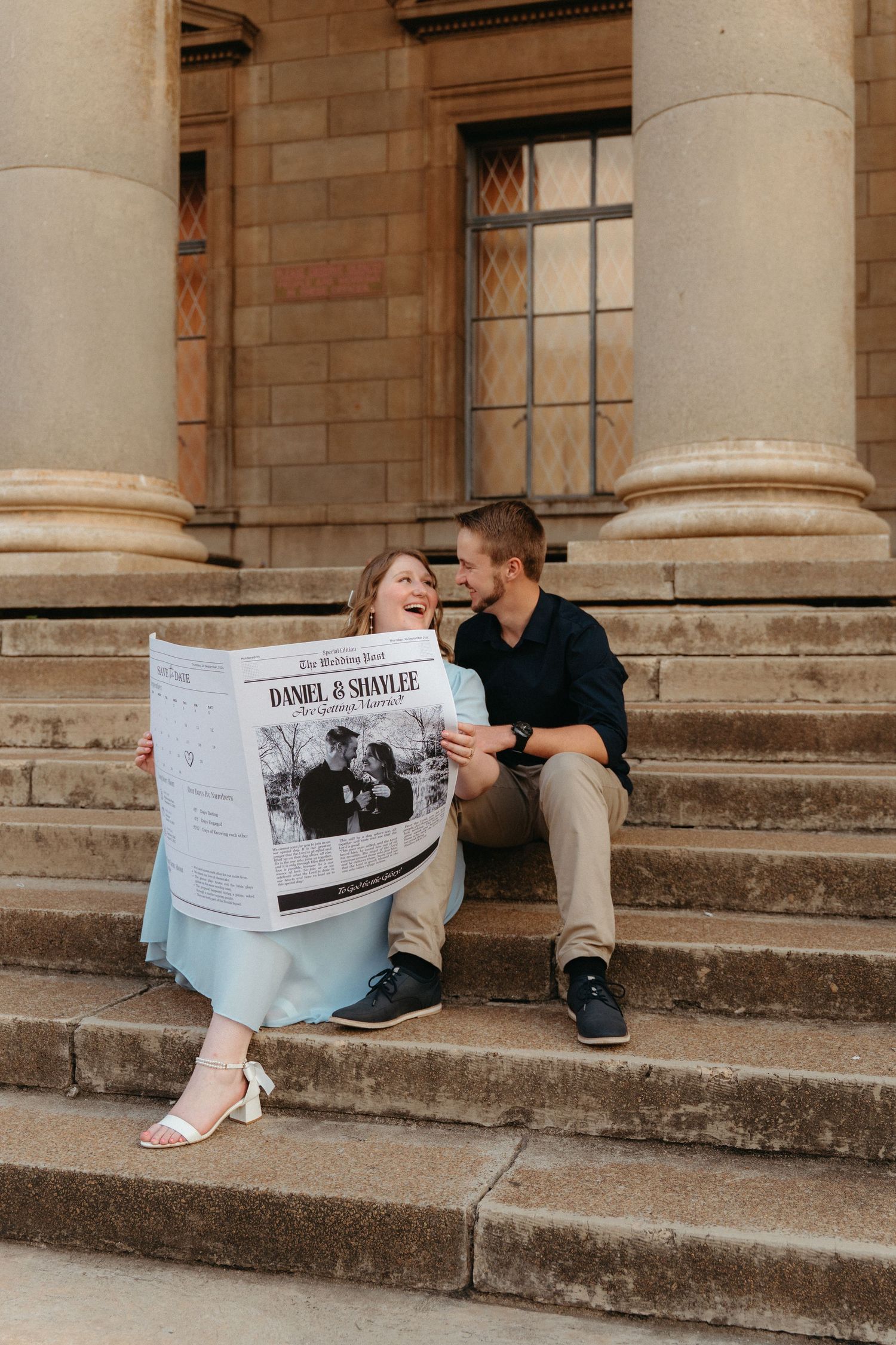 A couple sits on stone steps reading newspapers together in a vintage architectural setting.