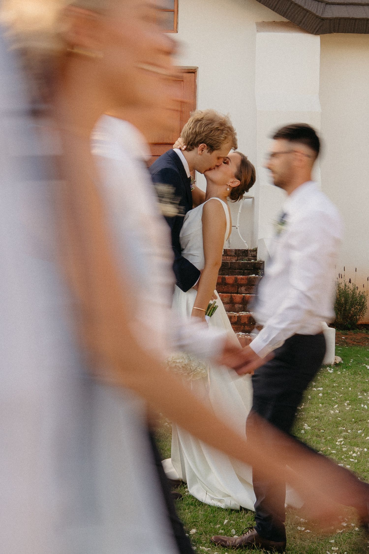 A motion-blurred sequence of wedding guests dancing at an outdoor reception shows movement and celebration.