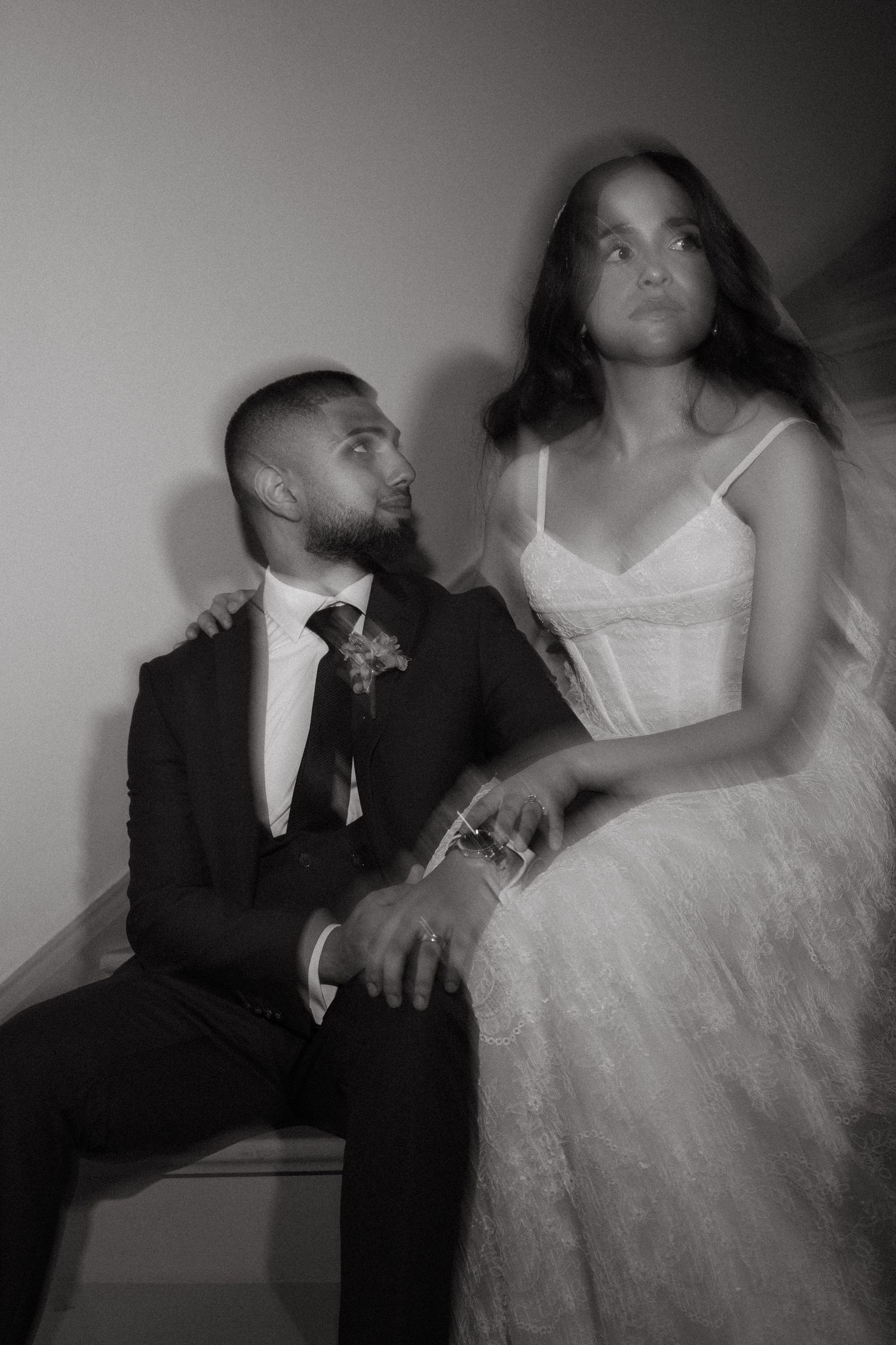 Black and white wedding photo of a groom in a suit and bride in a white gown posing together with a dreamy blur effect.