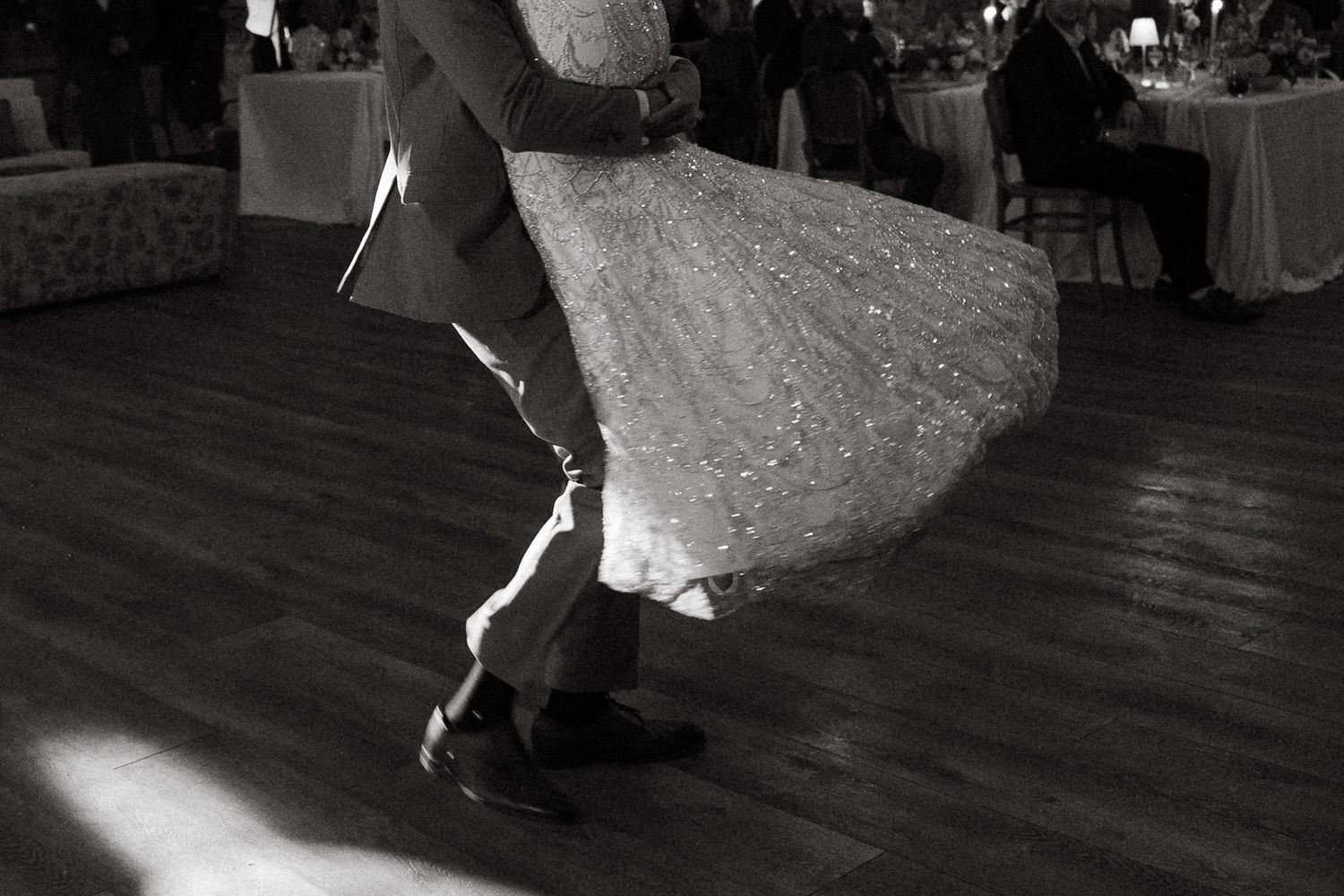 Black and white photo of a bride and groom sharing their first dance at a wedding reception.