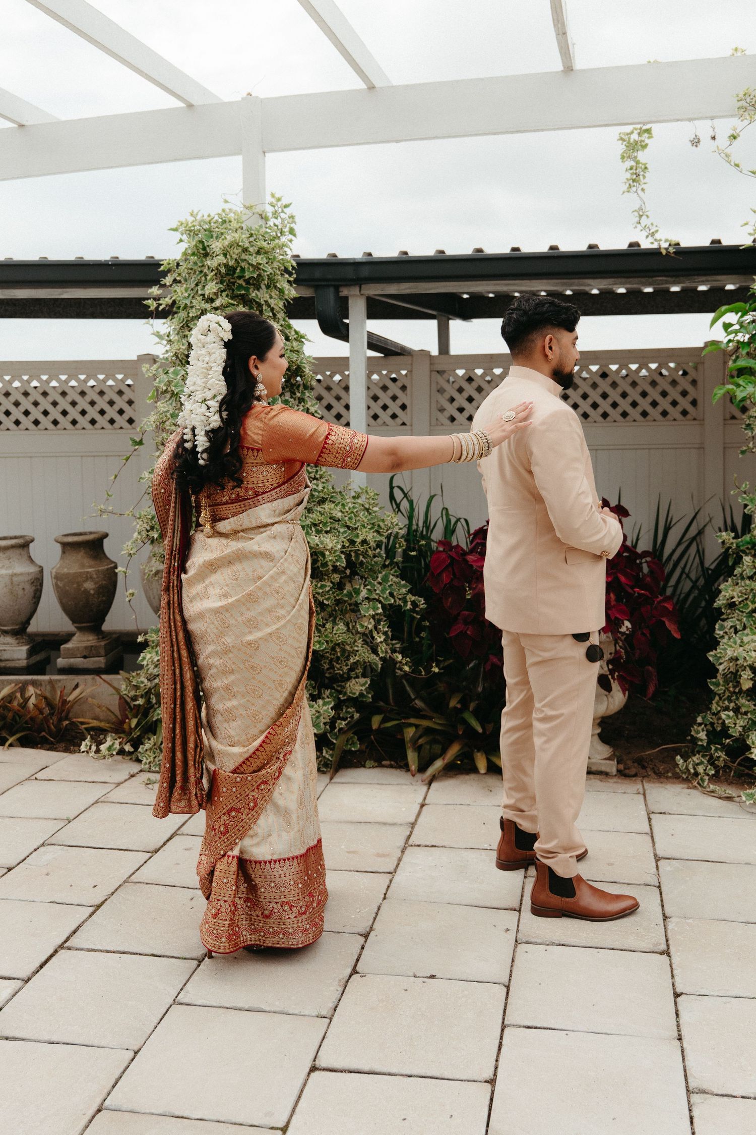 A couple in traditional South Asian attire performs a playful dance sequence on an outdoor patio.