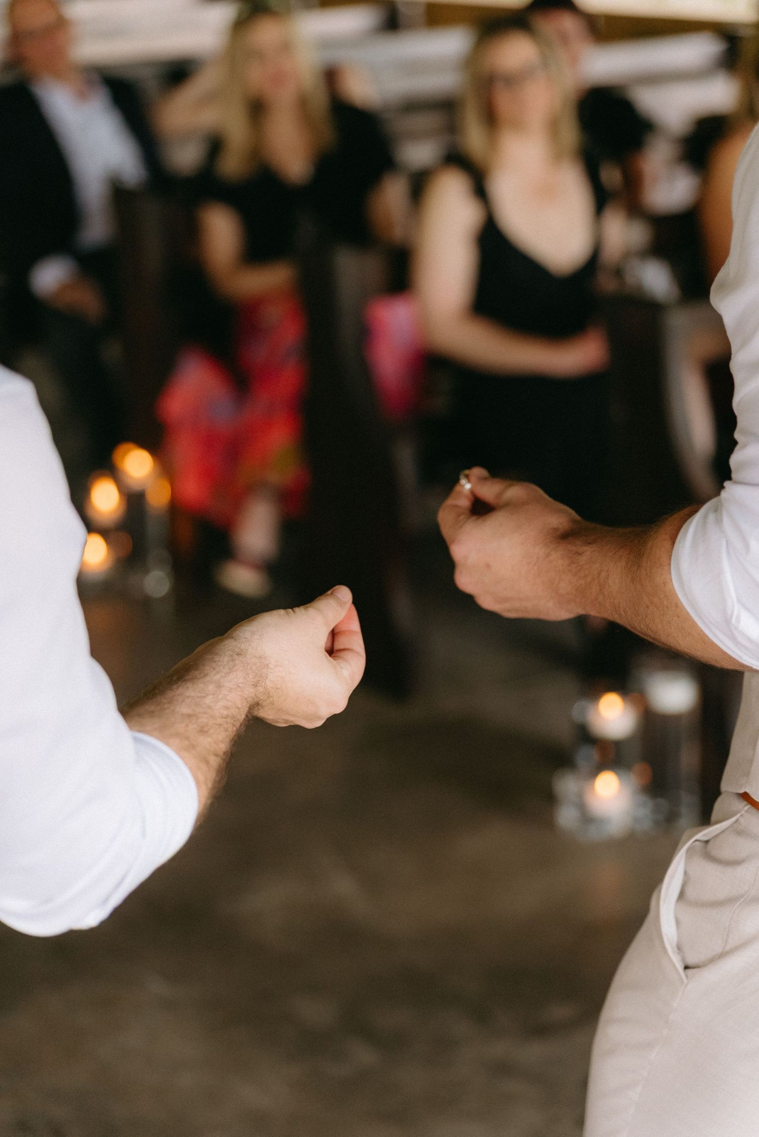 Close-up of hands during a wedding celebration in dimly lit reception venue.