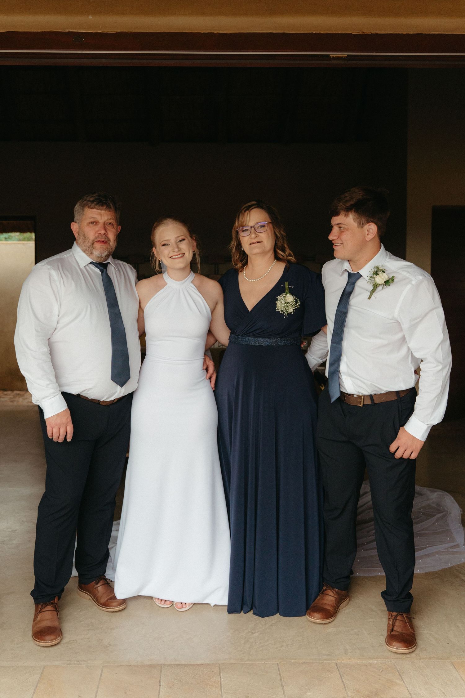 Wedding party members in navy and white formal attire pose together showing their shoes.