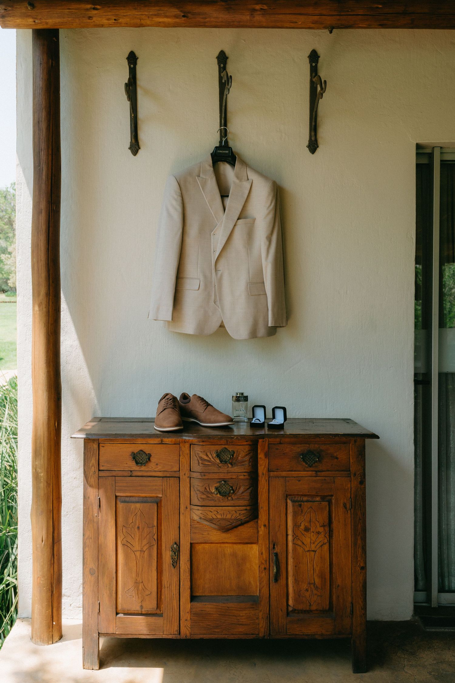 White suit jackets hanging above rustic wooden dressers along a wall in a minimalist room.
