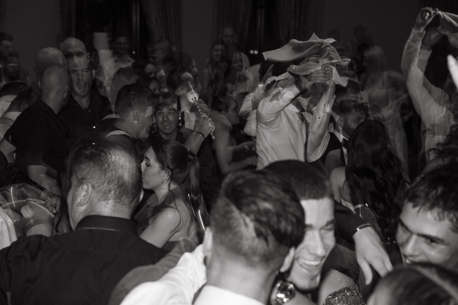 Black and white photo of a lively crowded dance party with people dancing and celebrating indoors.