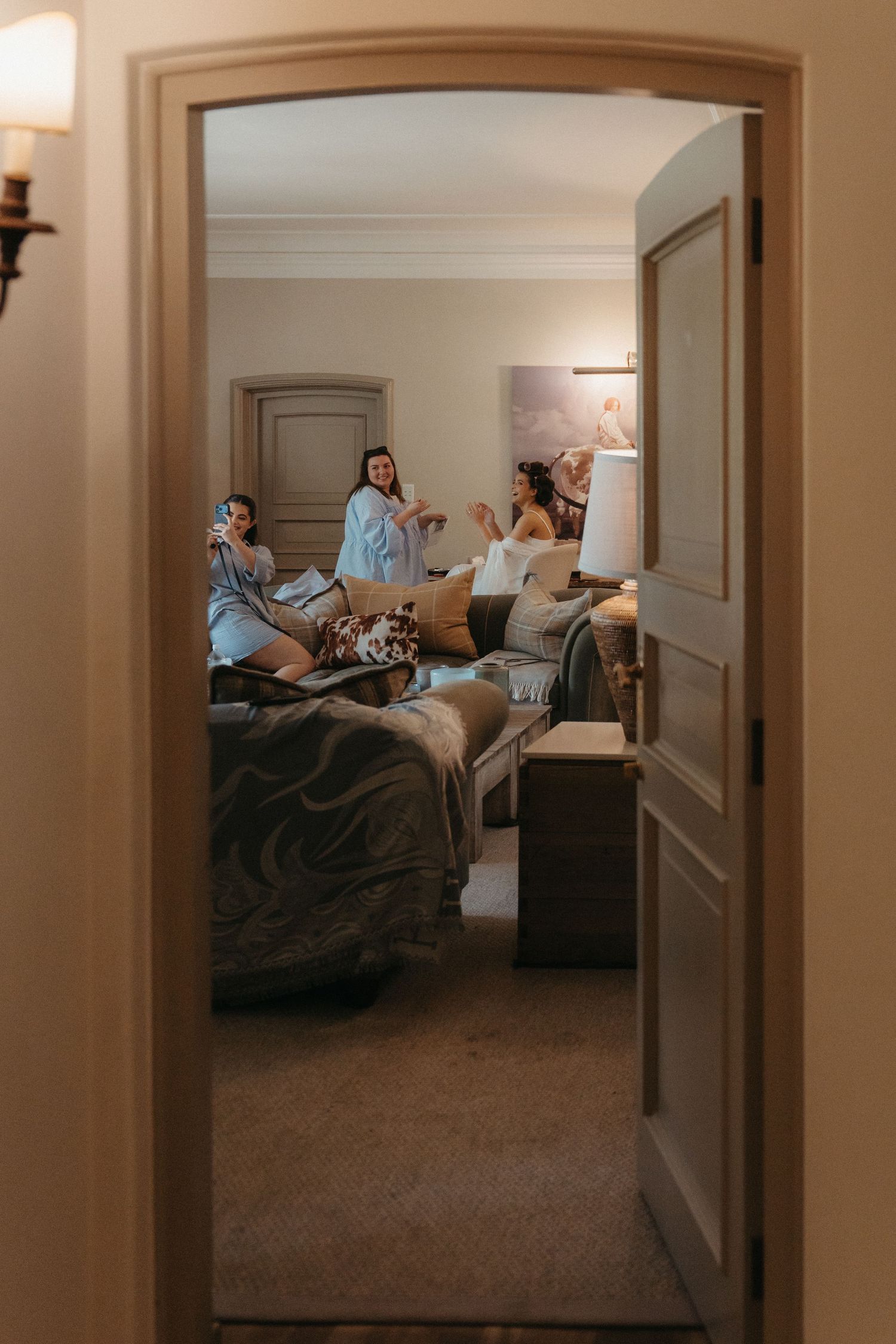Women in robes relaxing and chatting in a warmly lit room at Beechwood Gardens Johannesburg, viewed through an elegant doorway.