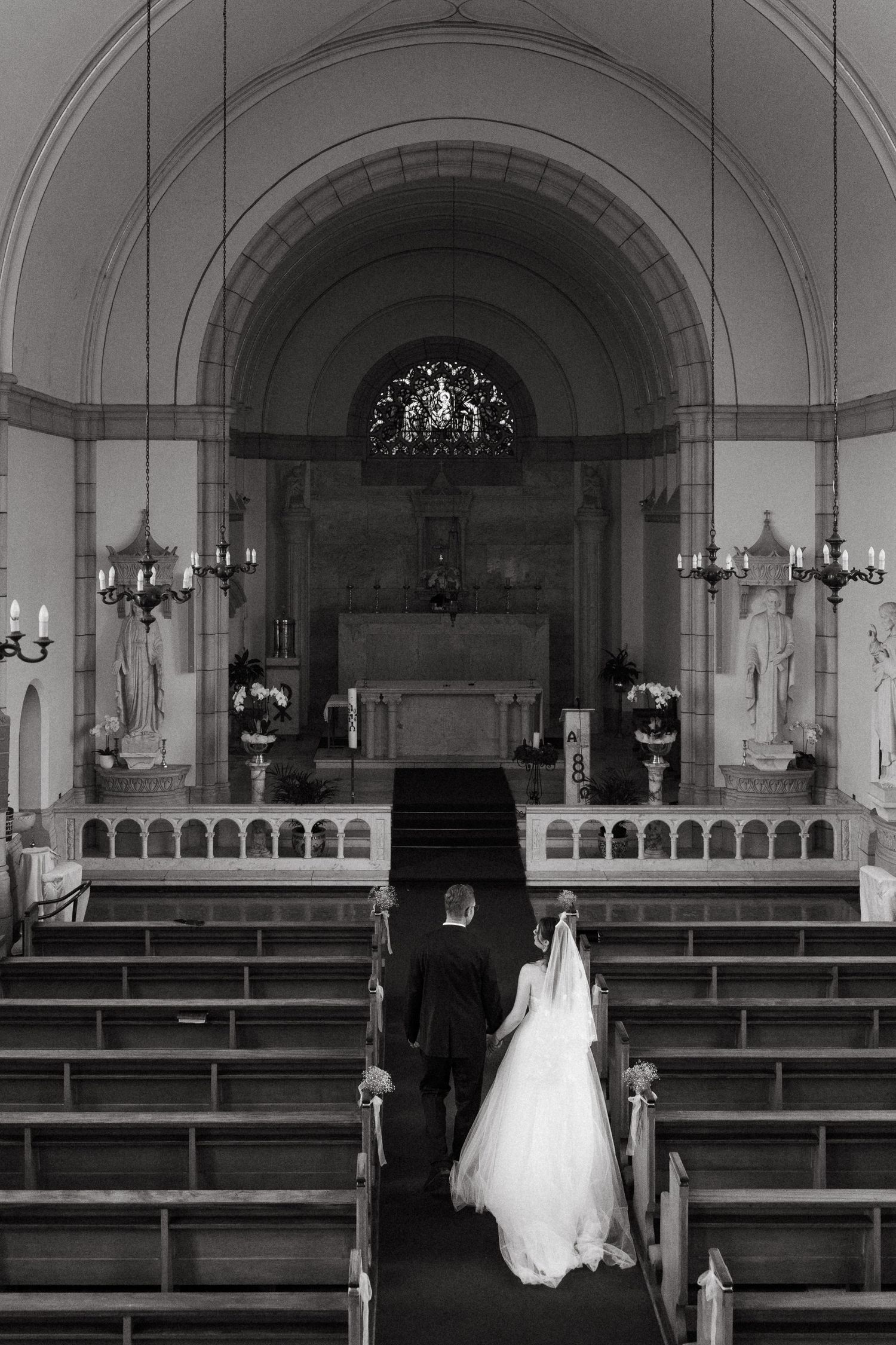A black and white panoramic sequence showing empty church pews leading to an altar in a traditional chapel interior.