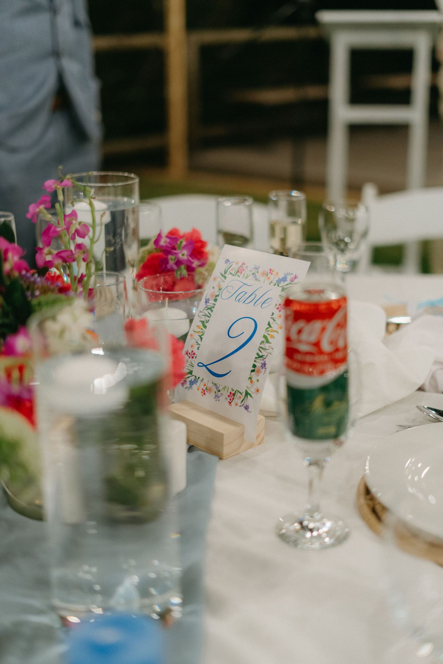 Wedding reception table settings with colorful floral centerpieces and handwritten place cards.