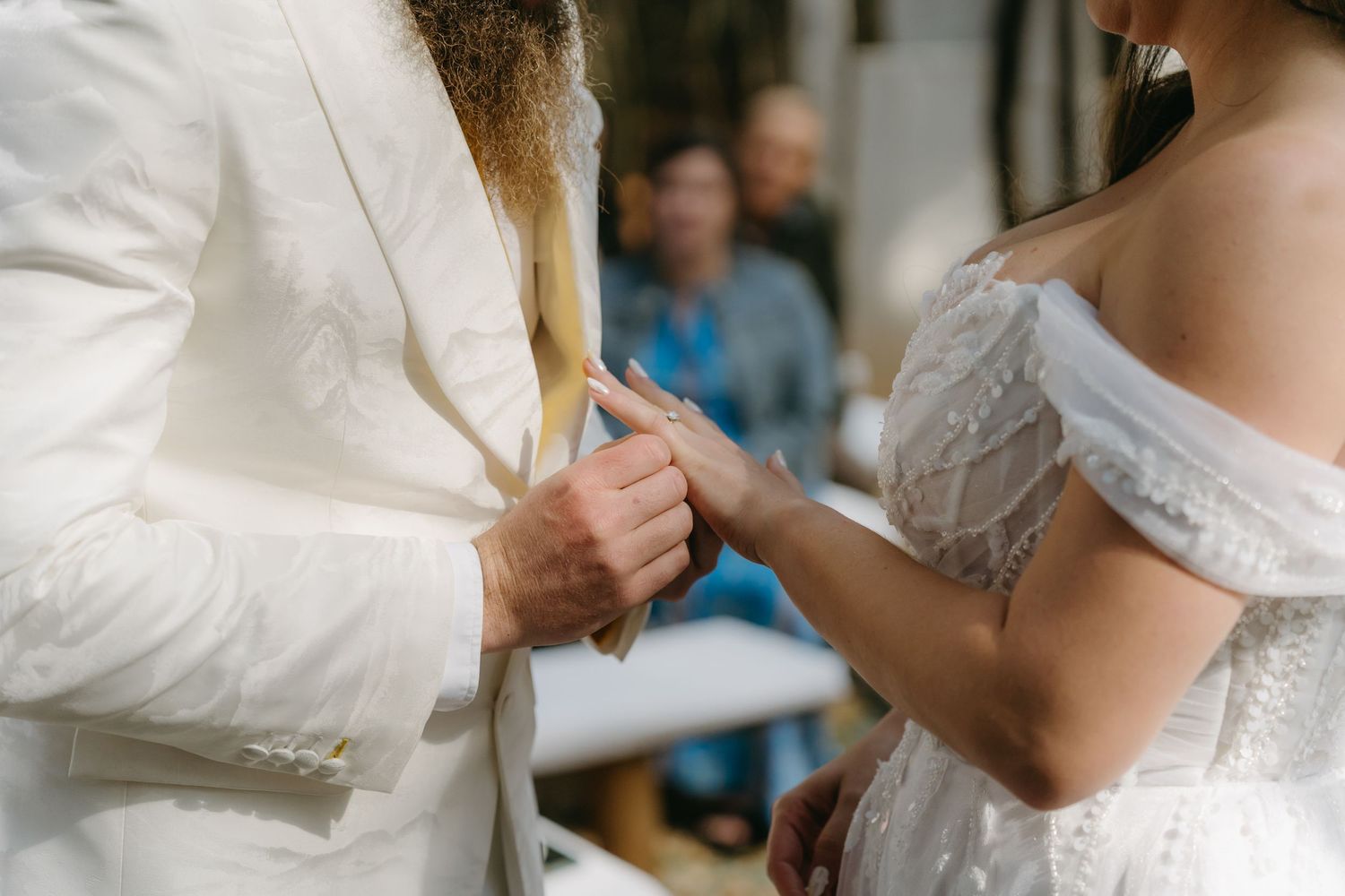 Close-up of couple exchanging rings during outdoor wedding ceremony.