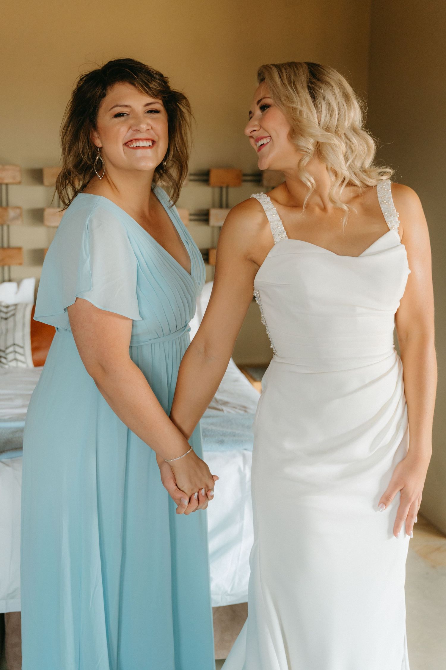 Bridesmaids in light blue dresses pose with bride in white gown during wedding preparations.