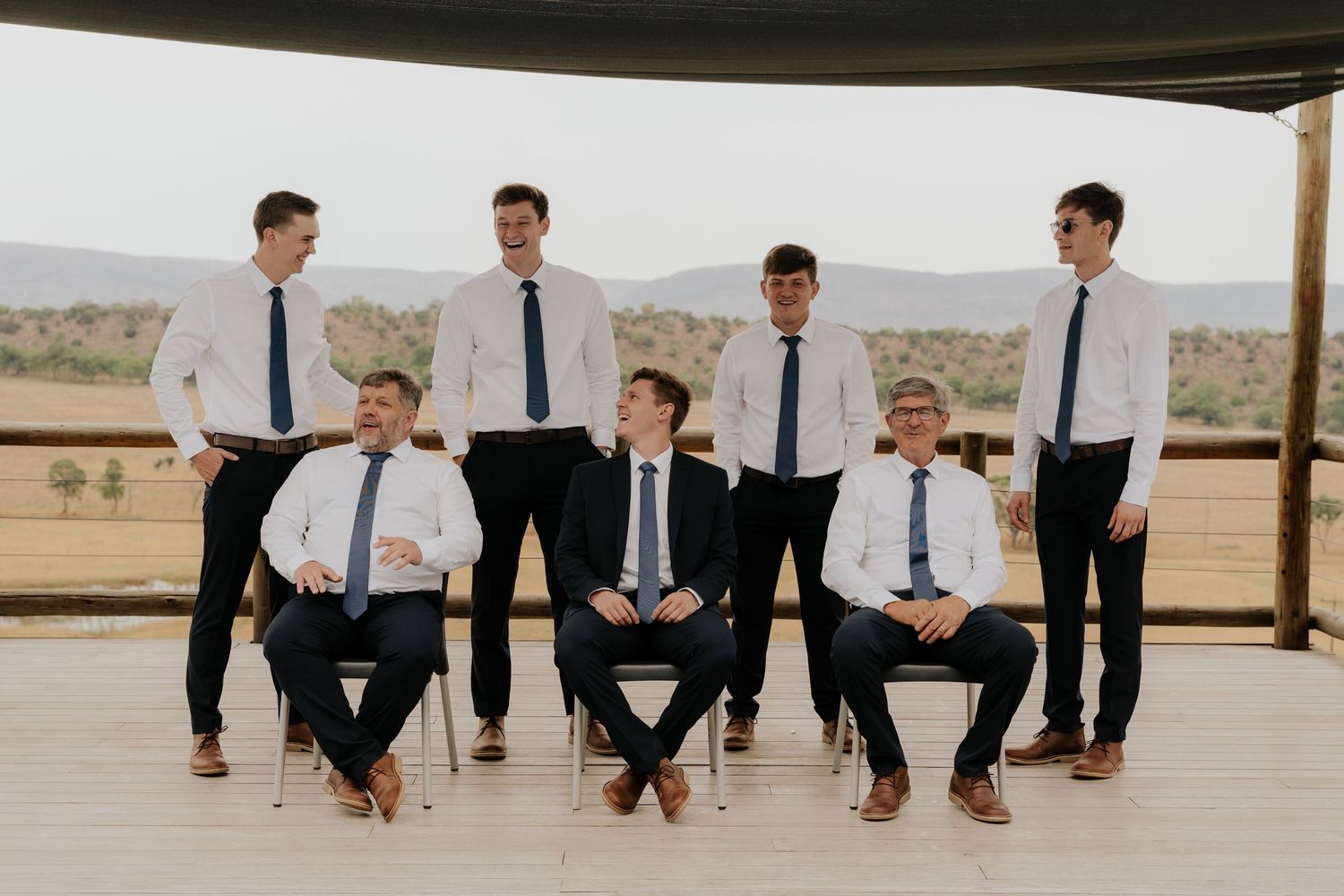 Groomsmen in matching white shirts and blue ties pose together for a formal wedding photo.