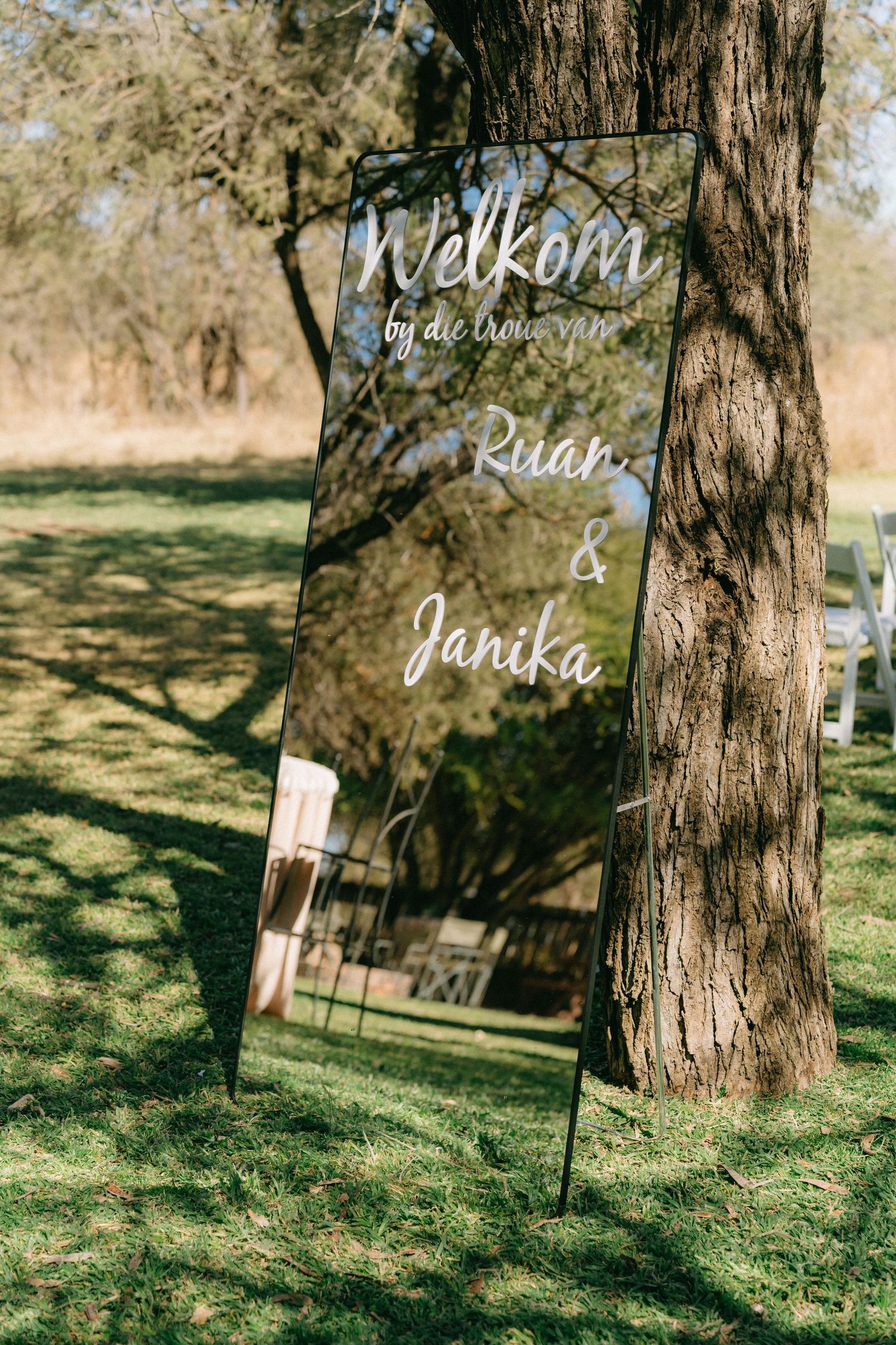Rustic wooden welcome signs displayed among trees at an outdoor wedding venue.