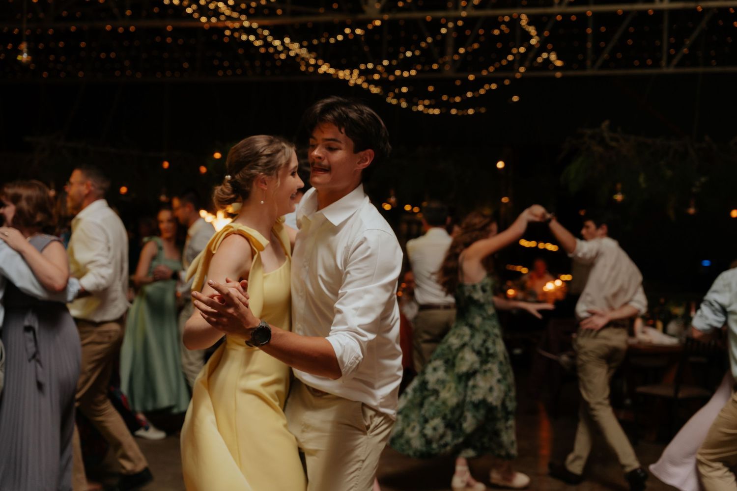 Couples dancing together at an elegant evening reception with twinkling lights in the background.