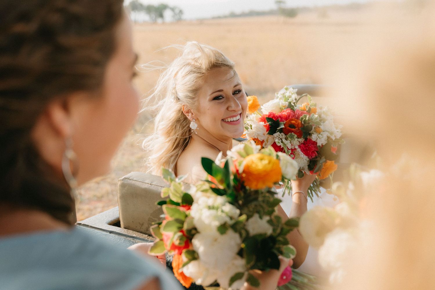 Colorful wedding bouquet with vibrant orange and red flowers against a soft blurred background.