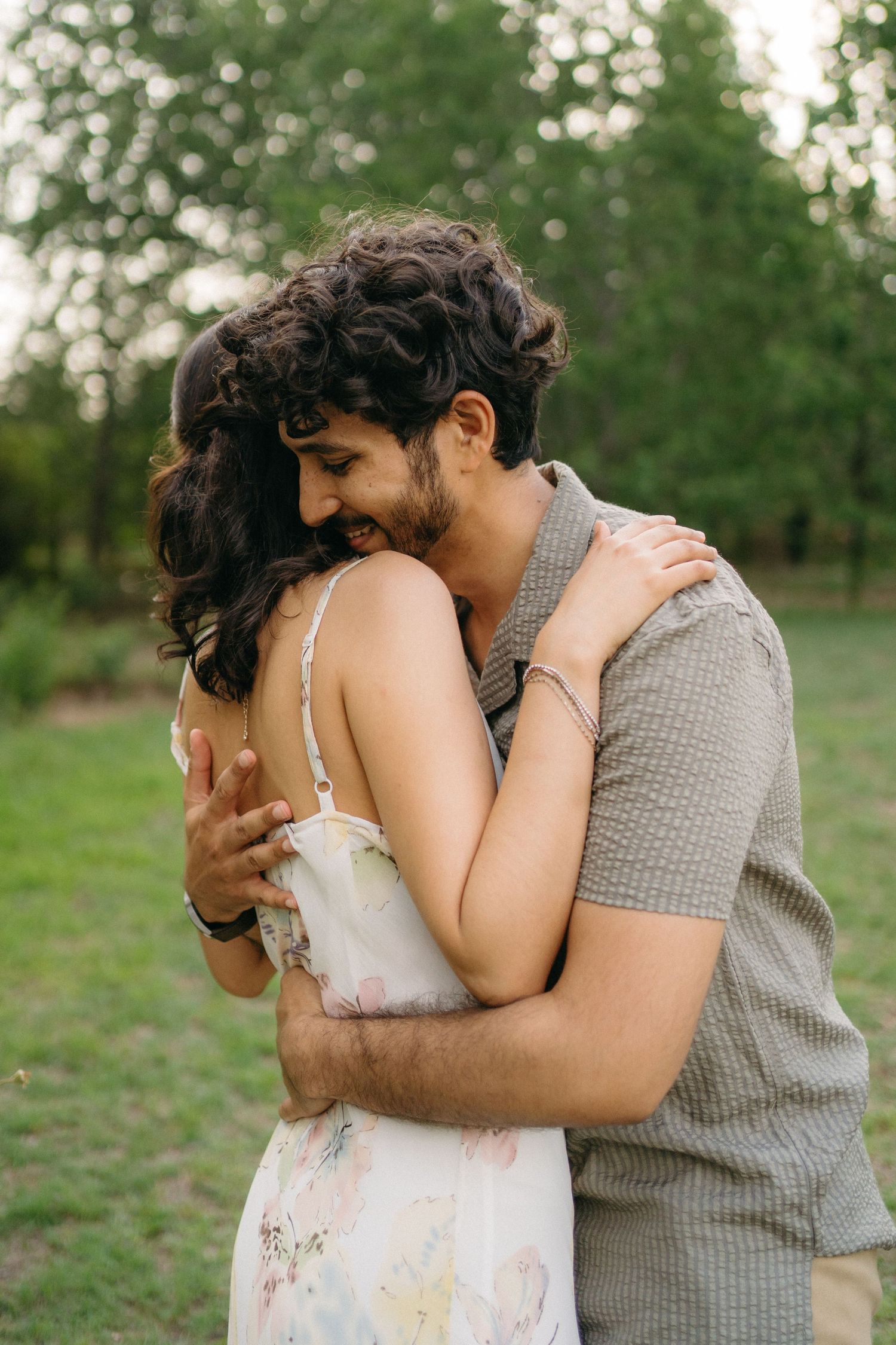A tender embrace between two people in casual summer attire outdoors.