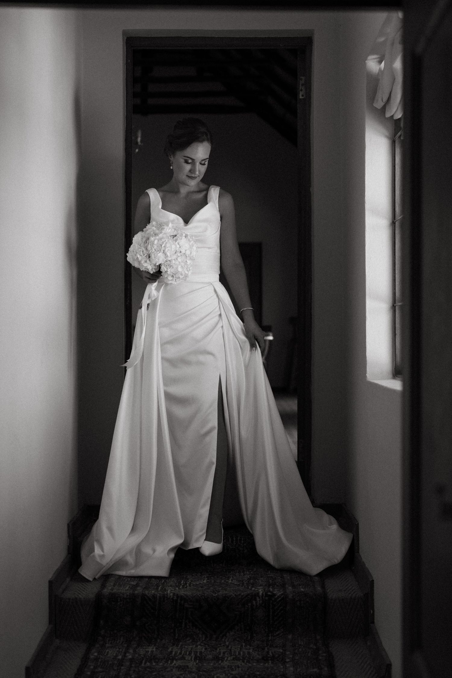 A dramatic black and white photo series shows a flowing white wedding dress in a dimly lit hallway.