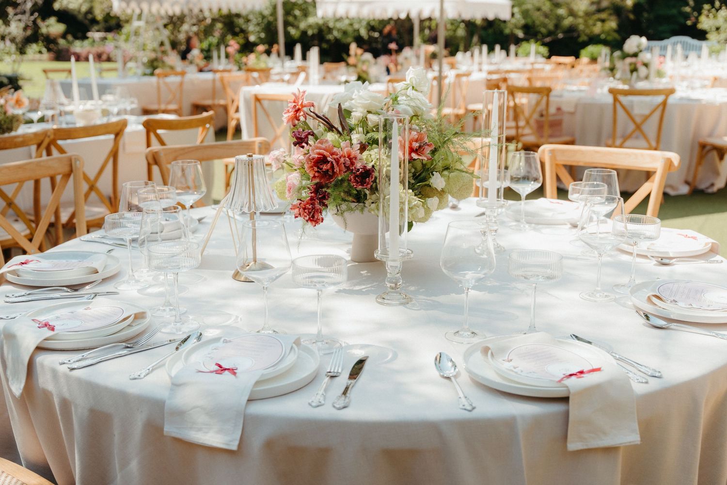 Elegant Johannesburg outdoor wedding reception table with white linen, crystal glassware, and a red floral centerpiece on a round table.