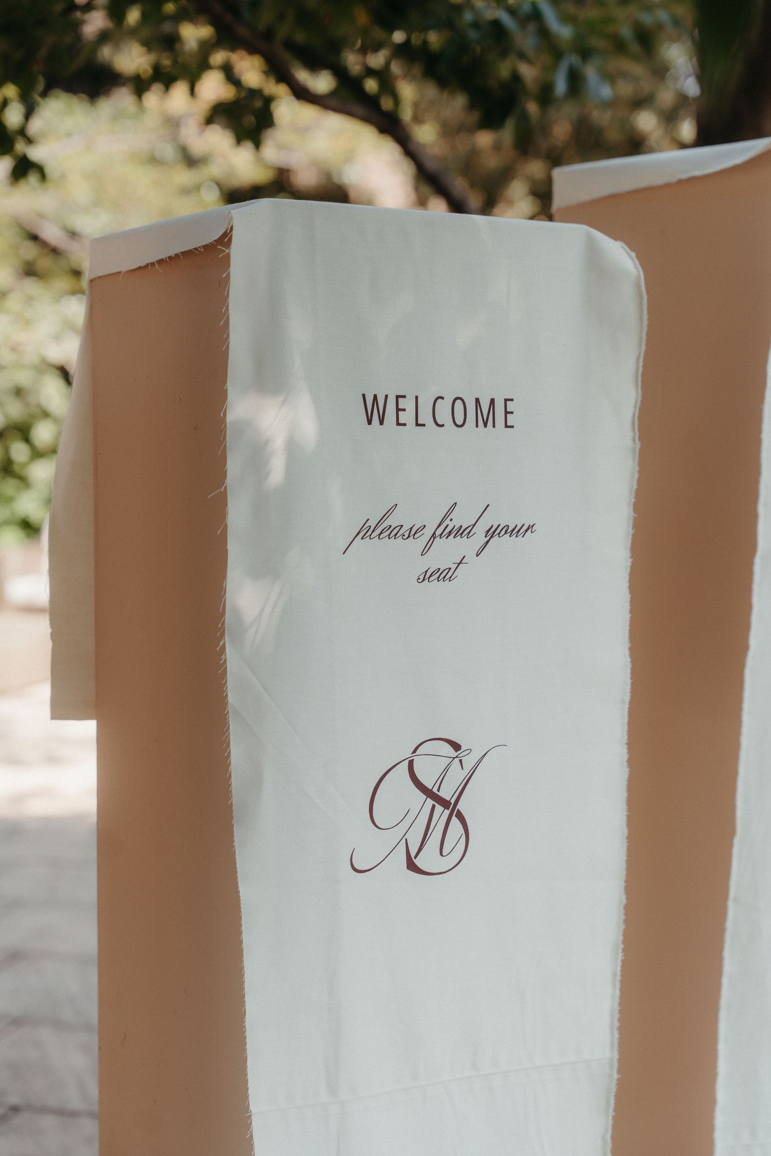 Elegant wedding welcome sign on white fabric with cursive monogram and 