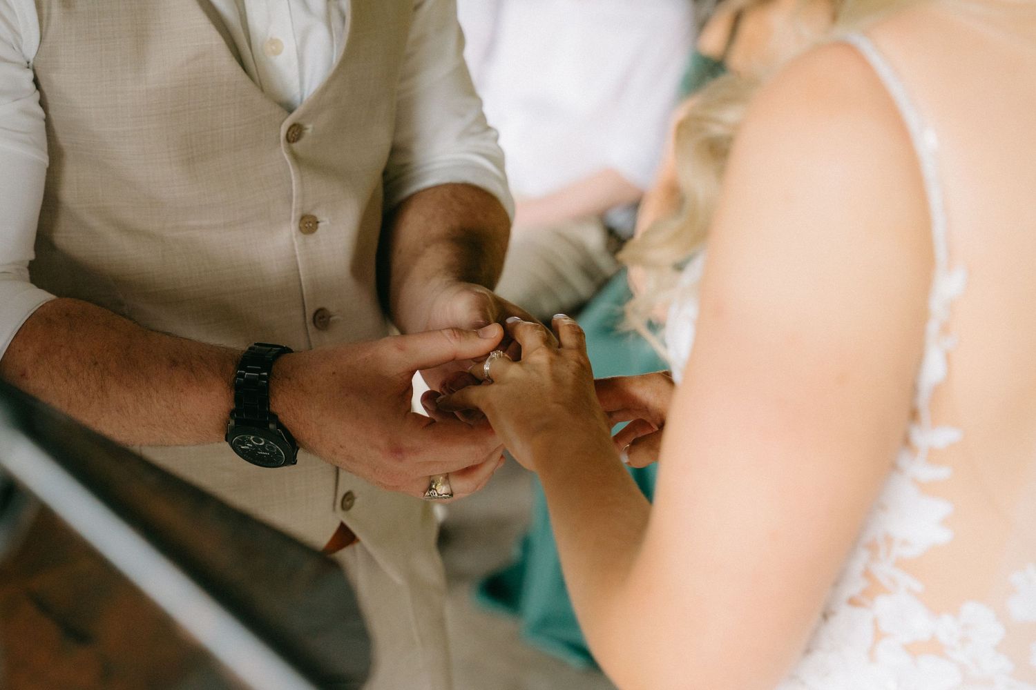 Close-up of hands exchanging wedding rings during an intimate ceremony moment.