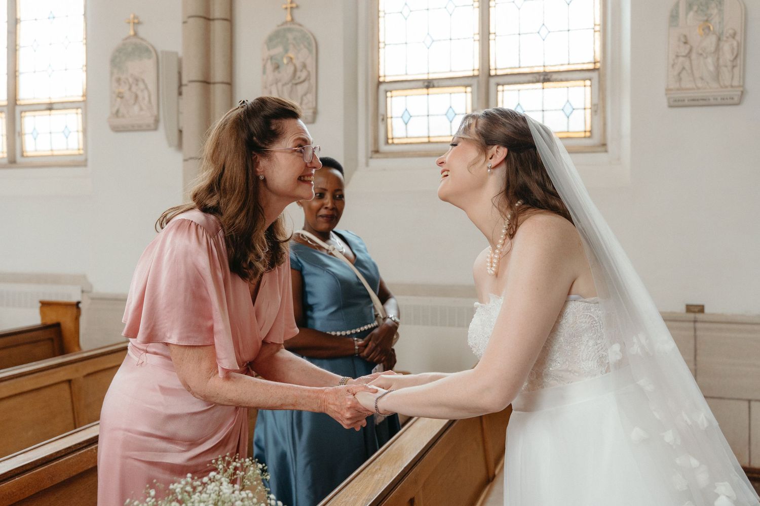A bride and her mom share an emotional moment in Nazareth House Chapel with white walls and vintage details.