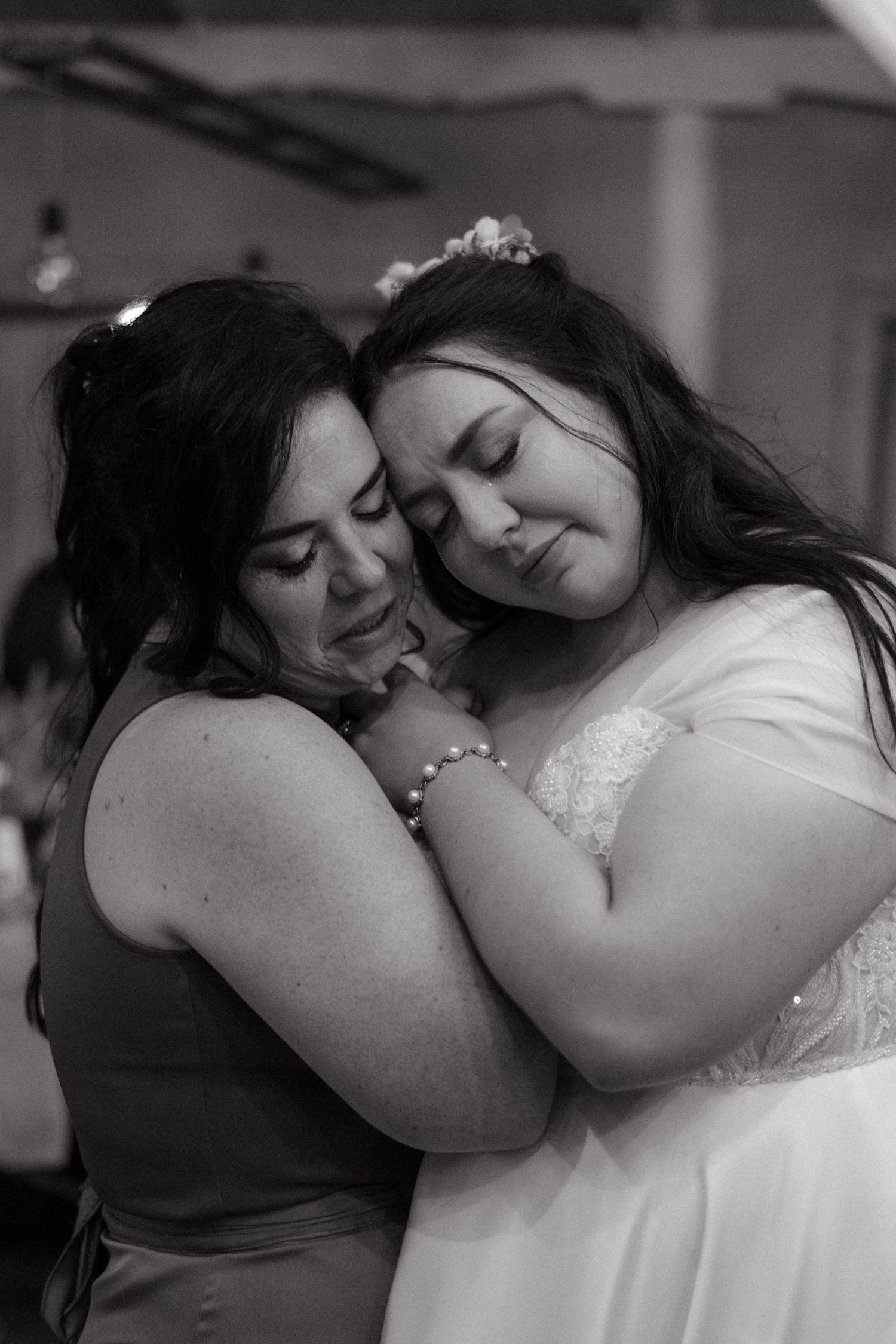Two people share an intimate moment in a tender embrace at what appears to be a celebration or wedding event.