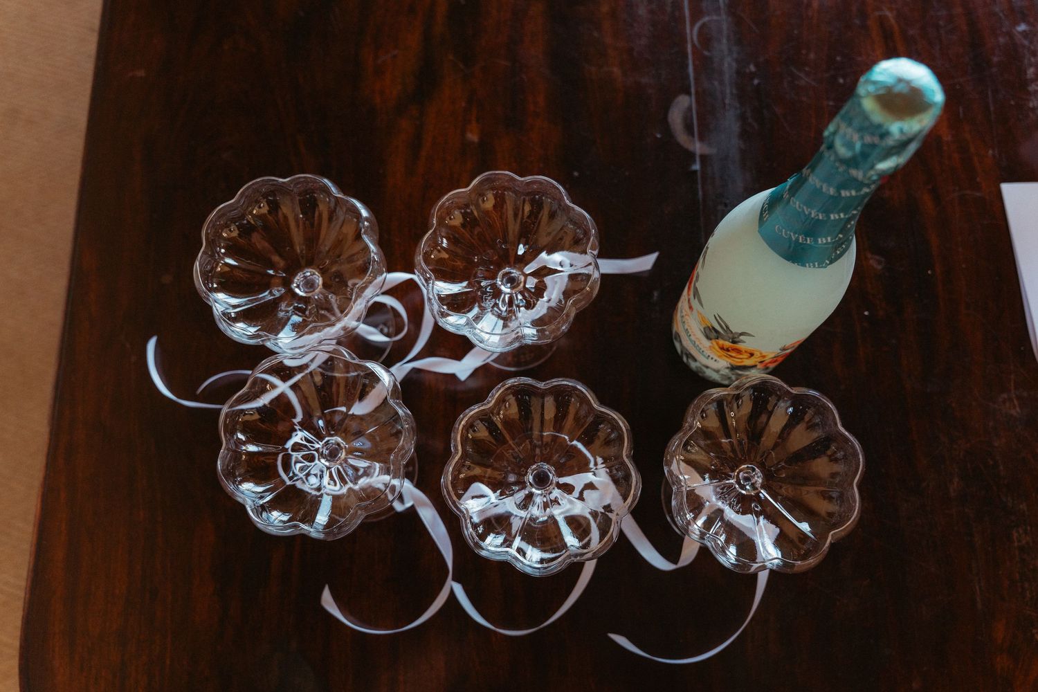 A collection of empty wine glasses hanging upside down from a wooden rack in a dimly lit bar or restaurant.