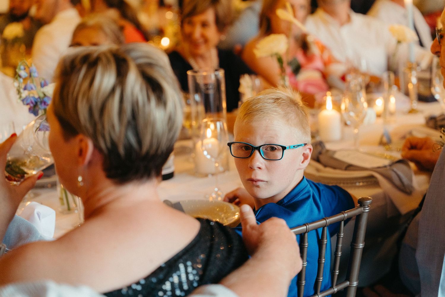 A group of people gathered around a candlelit dining table at an elegant dinner party celebration.