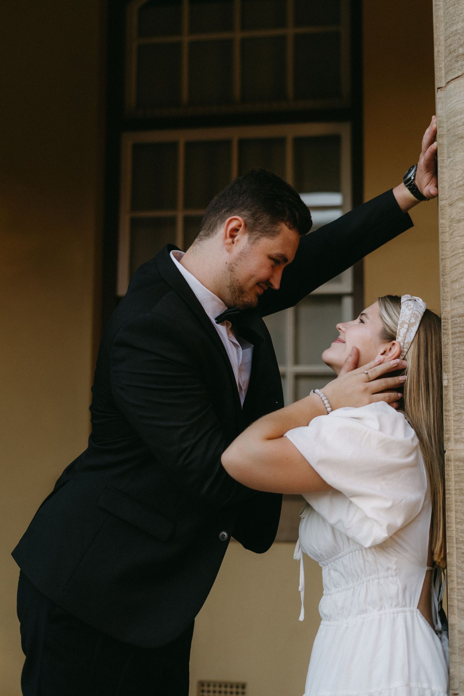 Romantic wedding portrait of couple embracing in vintage doorway with stone walls and dreamy lighting.