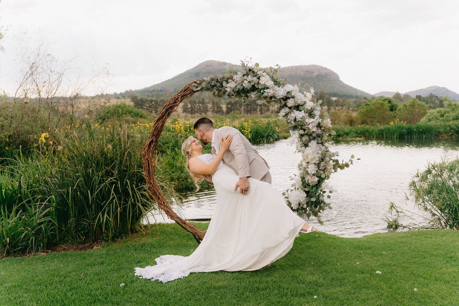 Wedding photos taken in a scenic outdoor setting with mountains and water in the background.