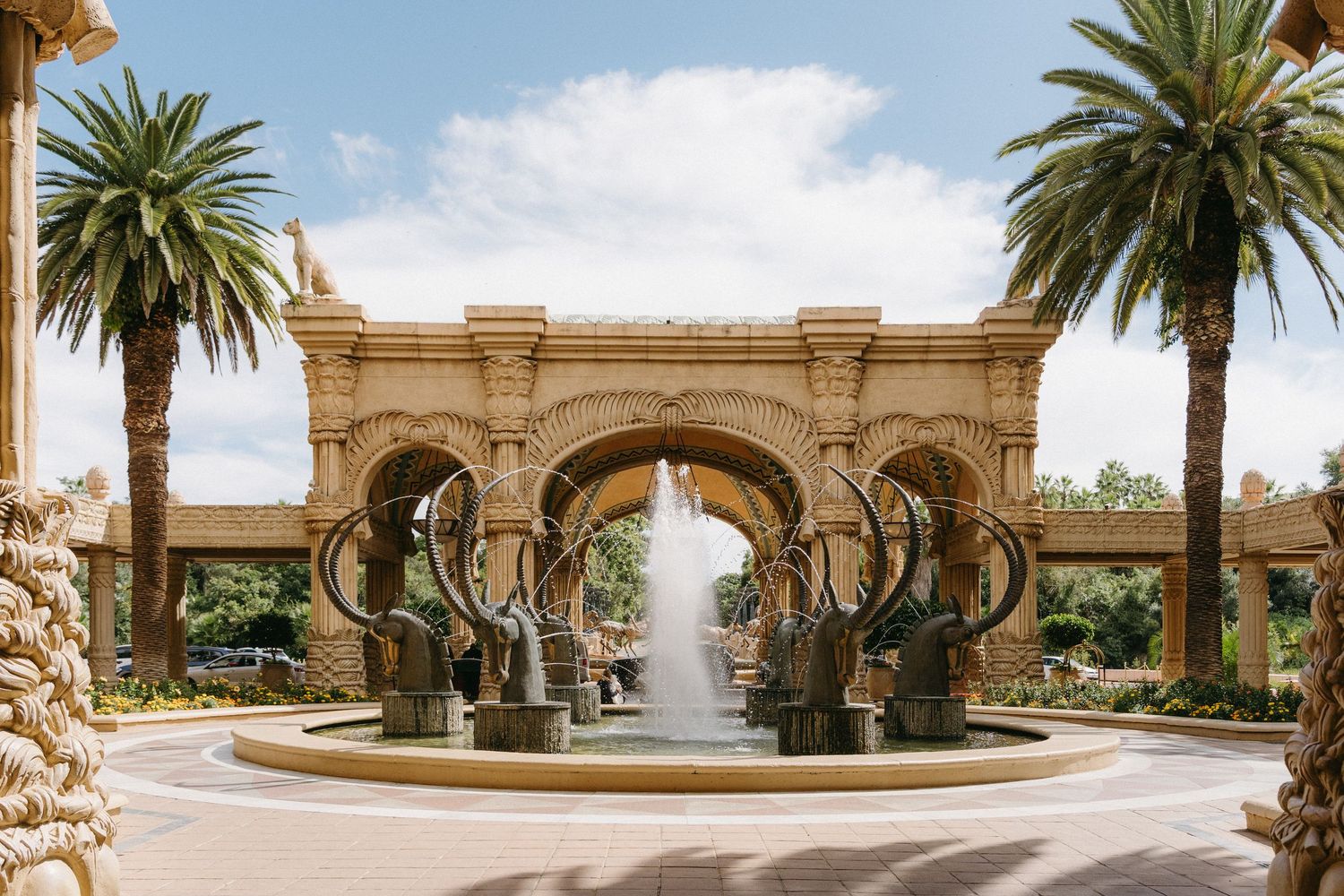 Panoramic view of a luxurious Mediterranean courtyard with palm trees, fountains and ornate Spanish colonial architecture.