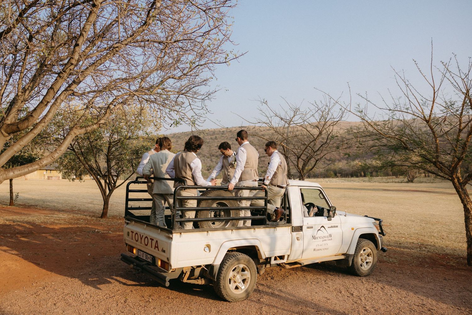 Safari vehicles parked in a line against a desert landscape at sunset.