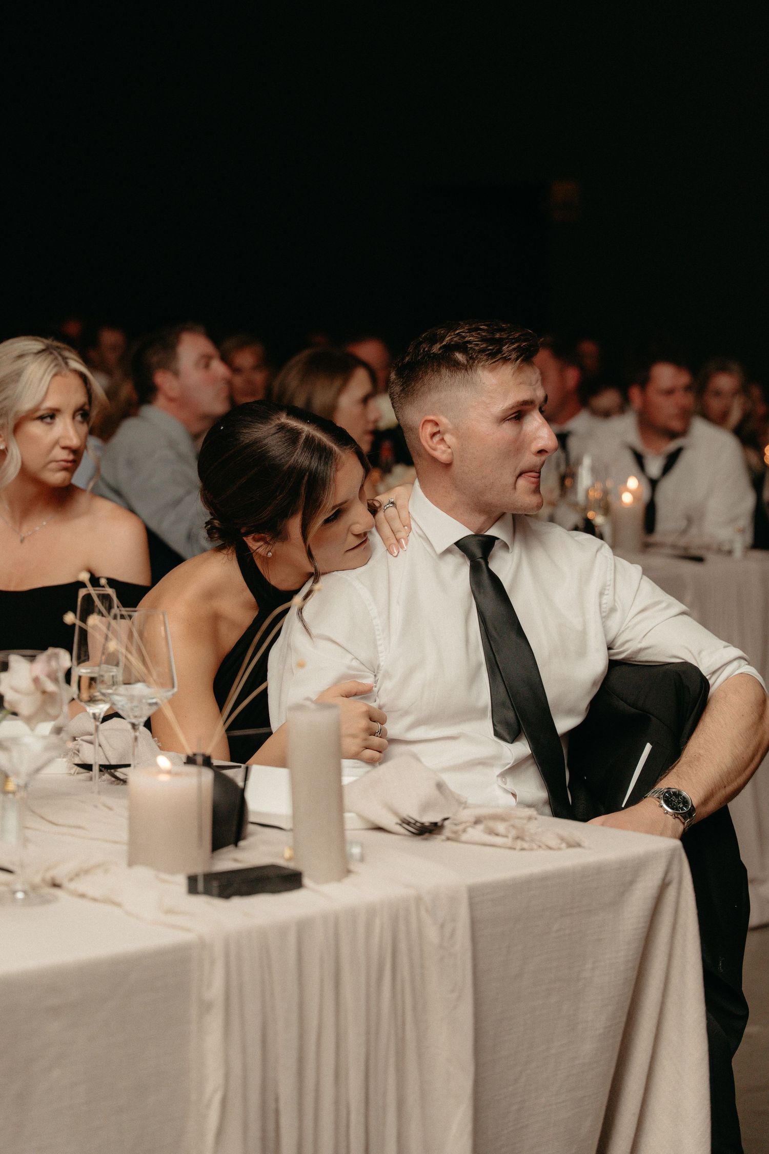 Wedding guests seated at a long table with white linens during a formal reception dinner.