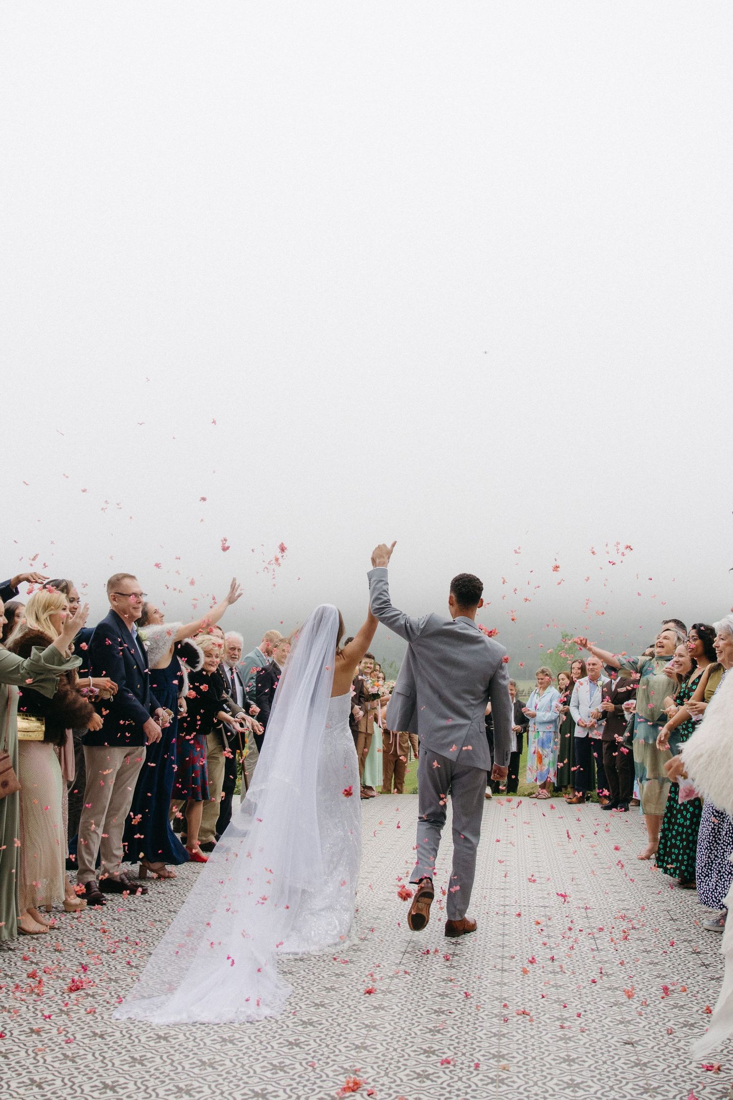Bride and groom walk through confetti shower with guests lining the aisle at Tafika Polo Farm