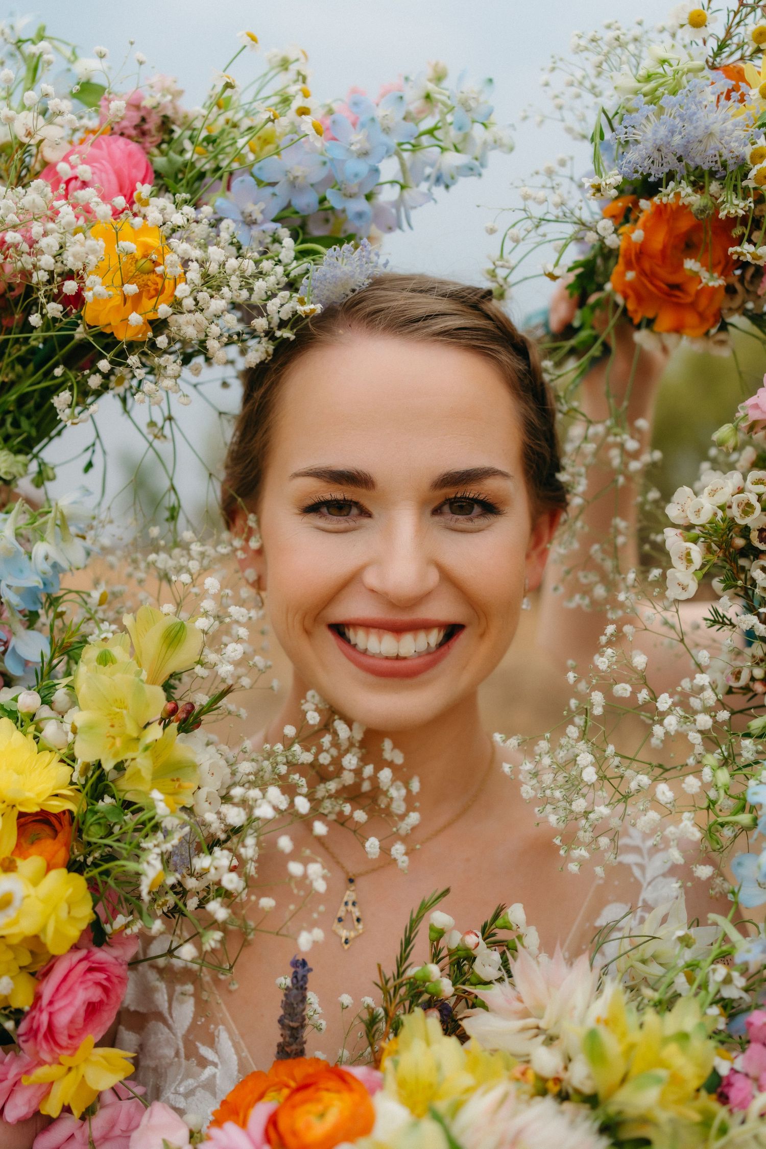 Colorful spring wedding bouquet with yellow, pink, and orange flowers frames joyful moment.