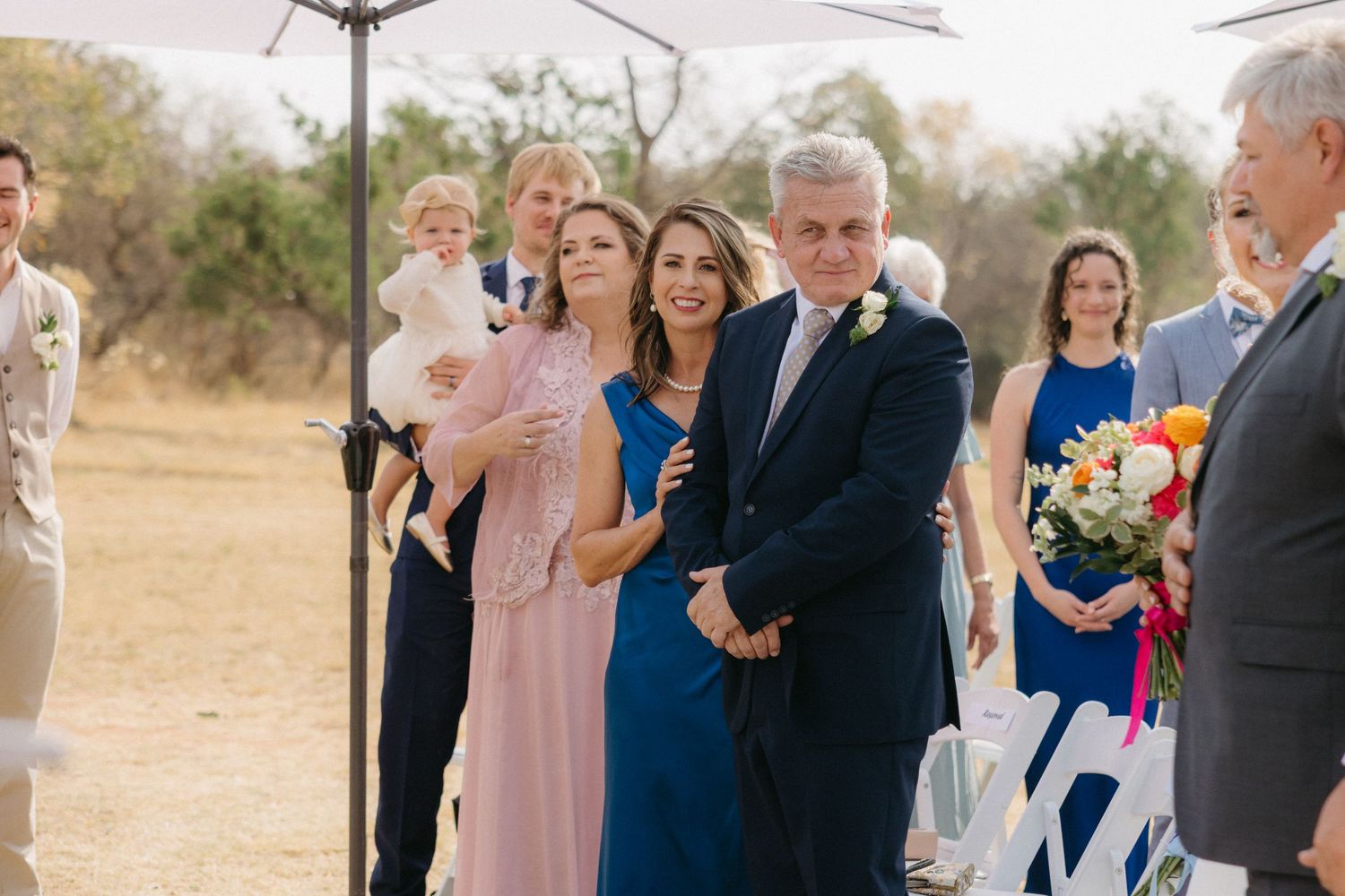 Wedding guests and family members gather for outdoor ceremony celebrations.