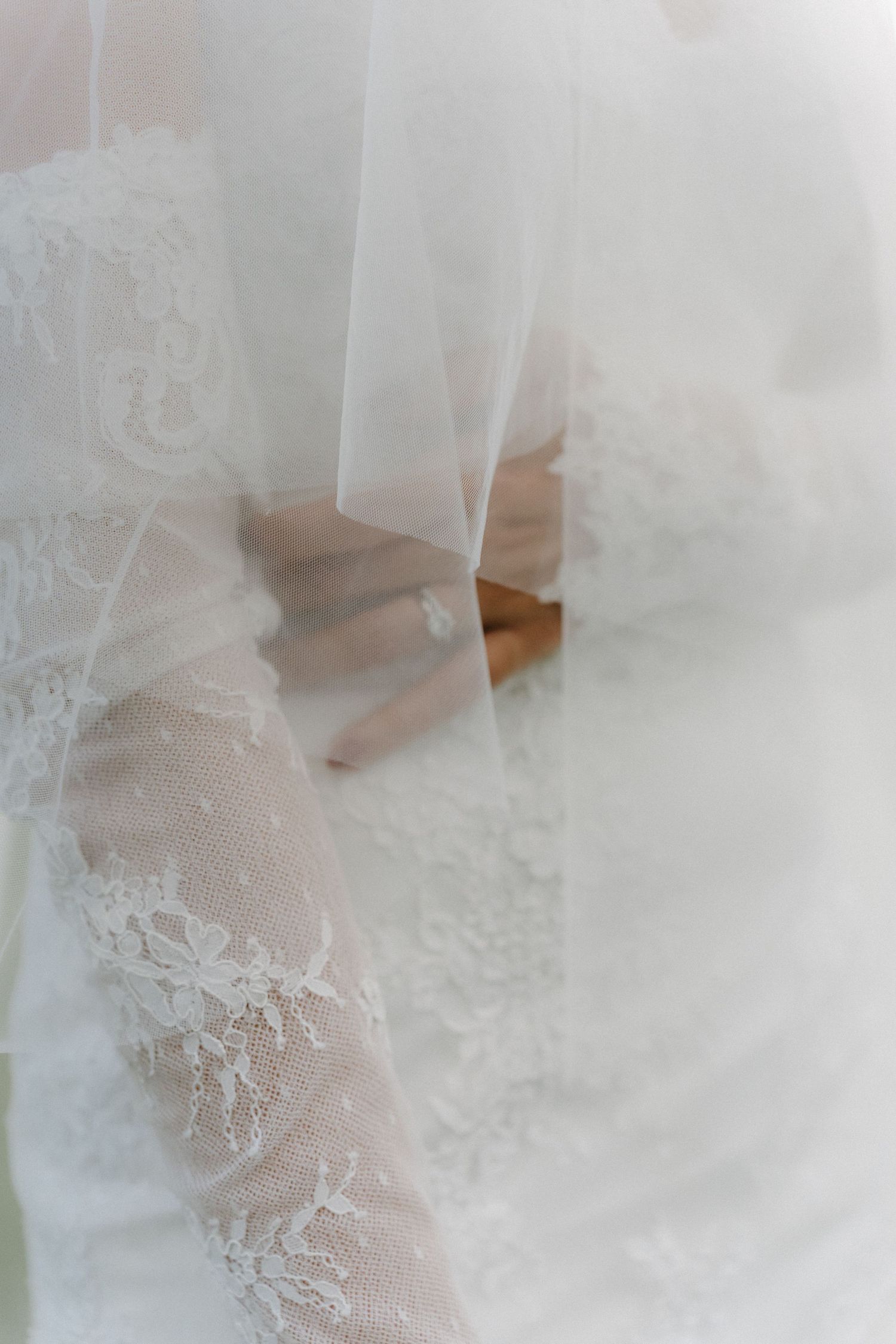 Delicate white lace details of a wedding dress veil with soft dreamy lighting.