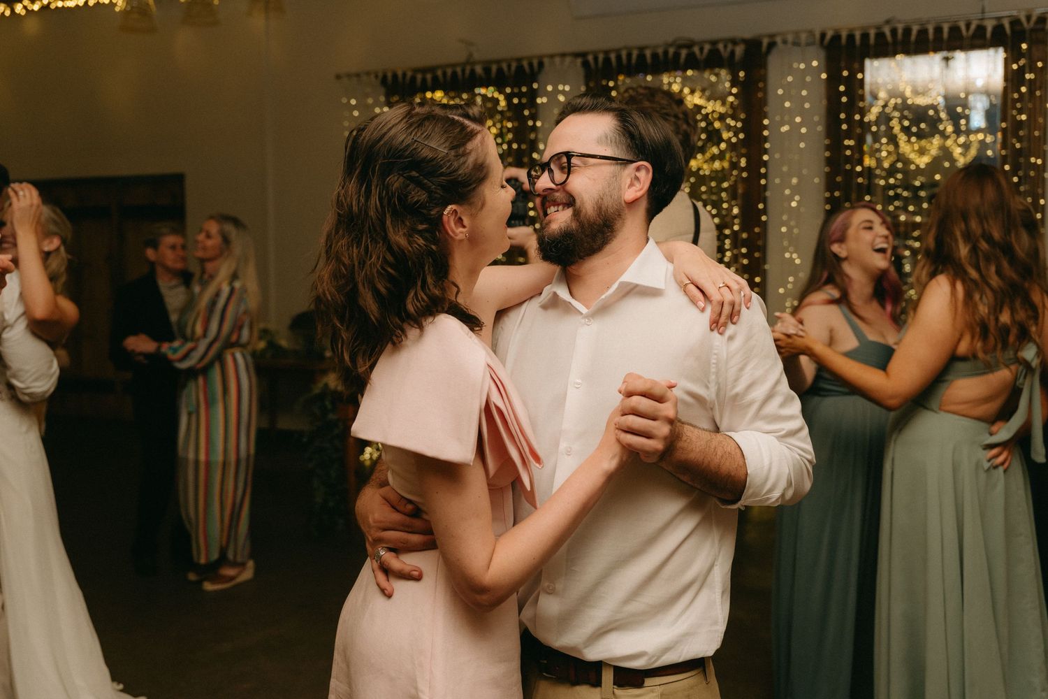 Wedding guests dance together during an evening reception celebration.
