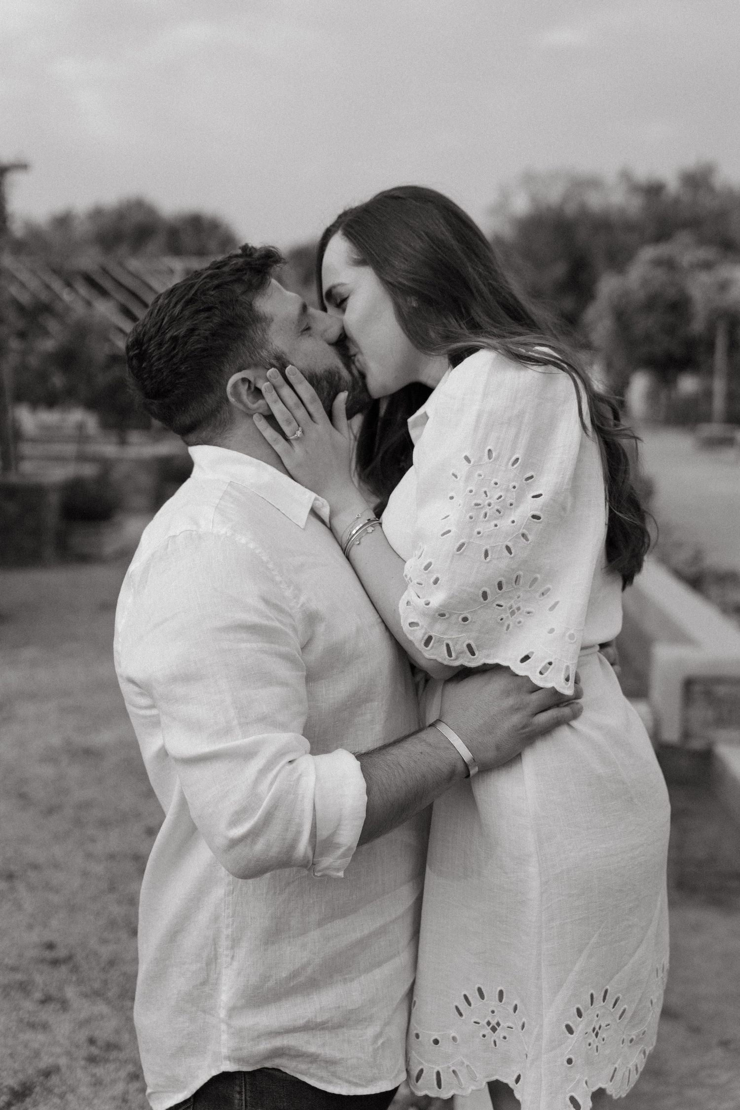 A black and white series showing an intimate moment between two people in white outfits outdoors.