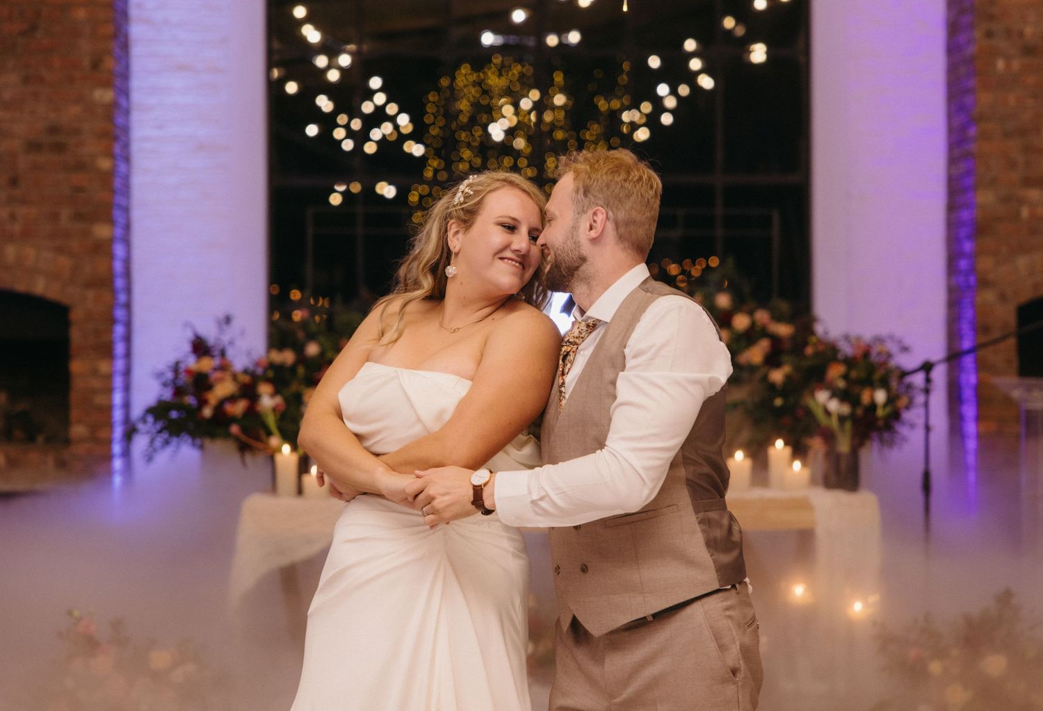 Couple sharing a romantic dance moment under twinkling lights at their wedding reception.