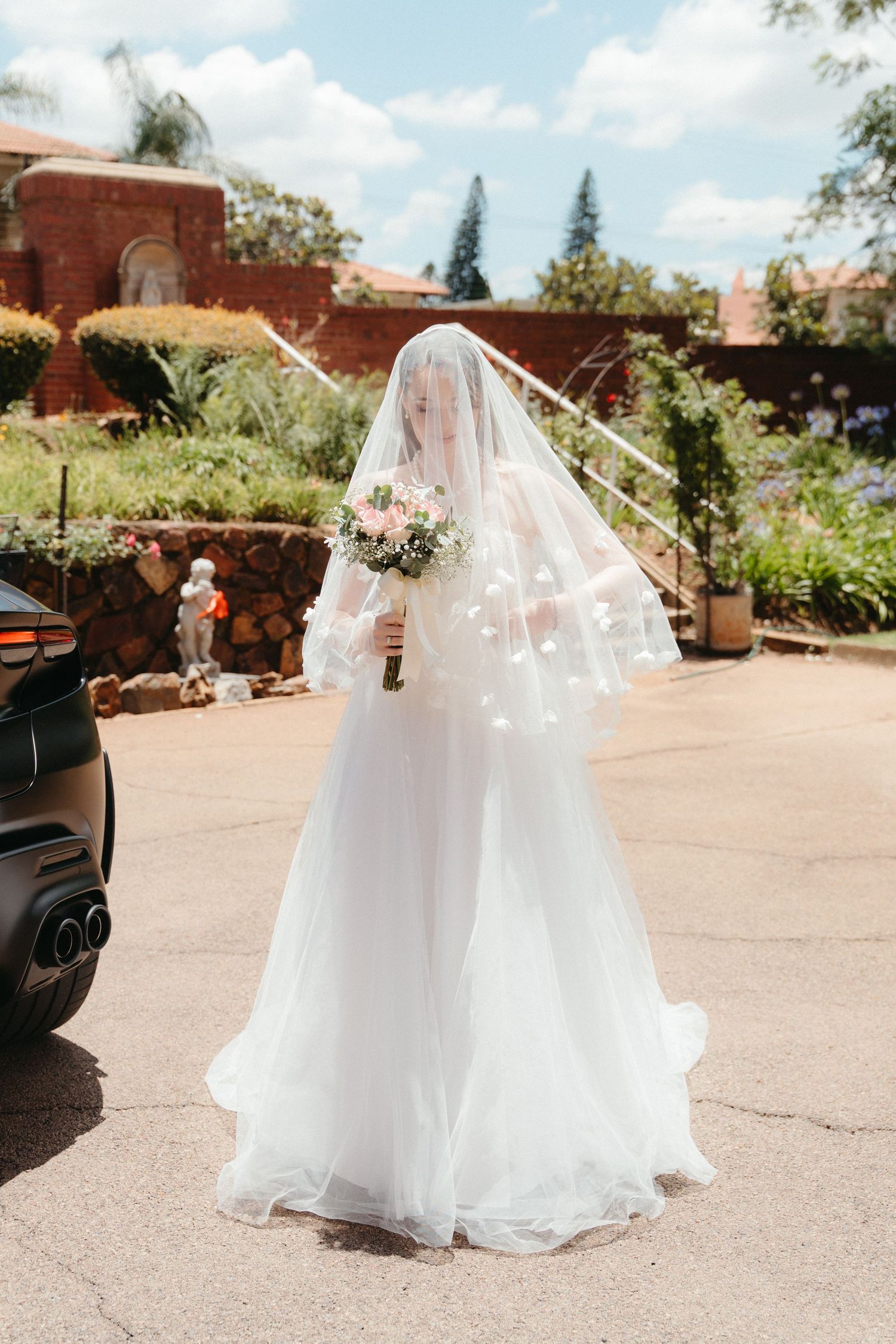 A bride in a flowing white wedding dress with a long veil prepares to enter Nazareth House Chapel