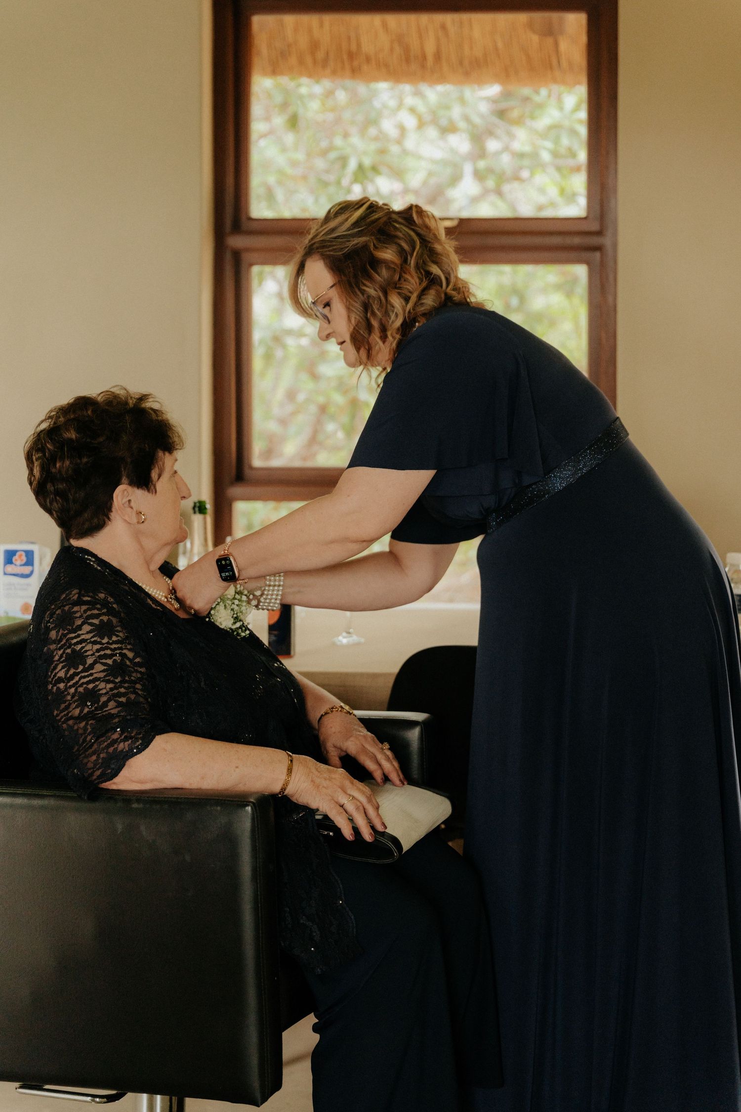 Wedding preparation scene with people in black attire helping with final touches.