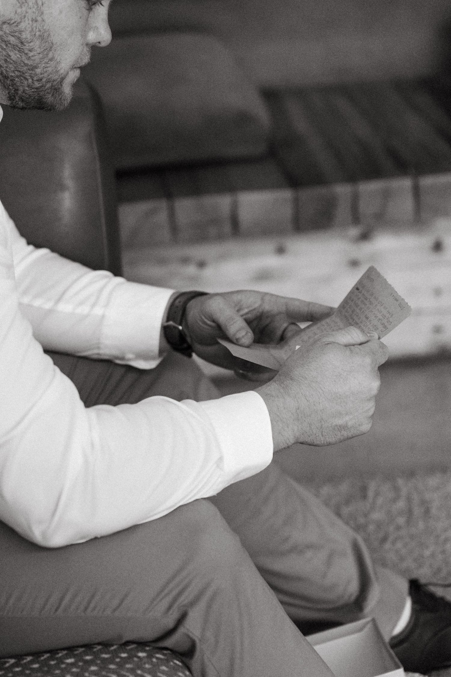 Black and white photo of someone reading a note or card while seated.