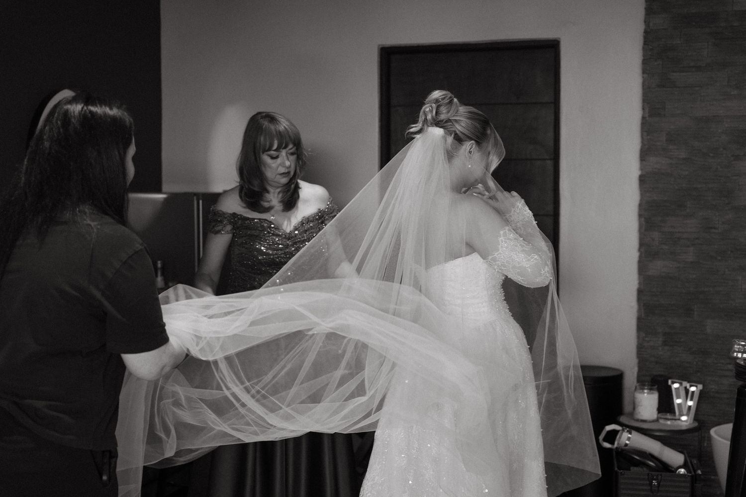 Black and white photo of bridesmaids helping bride adjust her veil before the ceremony at Simbali Lodge, Pretoria