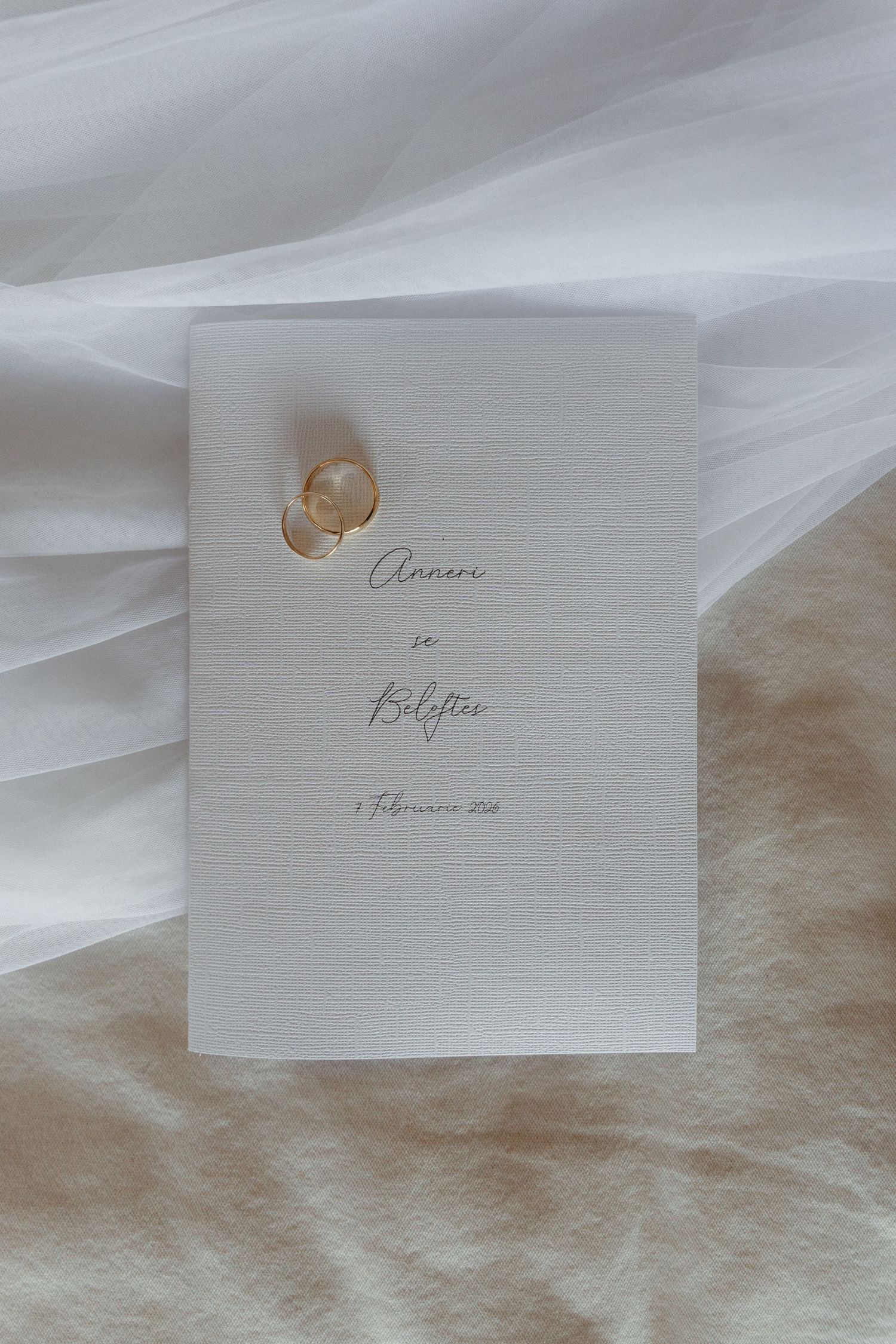 Elegant handwritten calligraphy text on white paper with soft flowing fabric and delicate lighting.