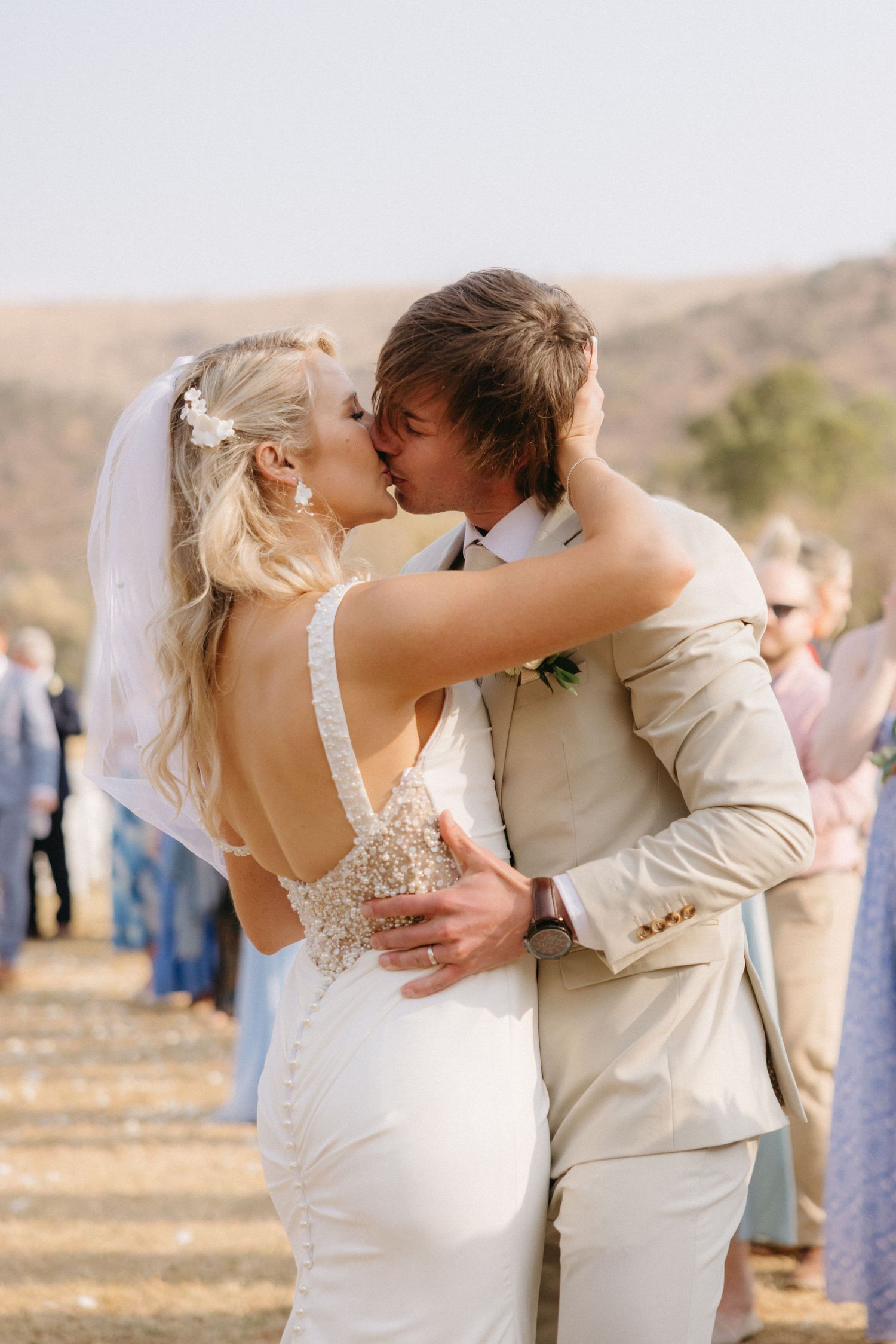Bride and groom share first kiss outdoors at Mountain View Lodge in Limpopo with guests celebrating behind them.