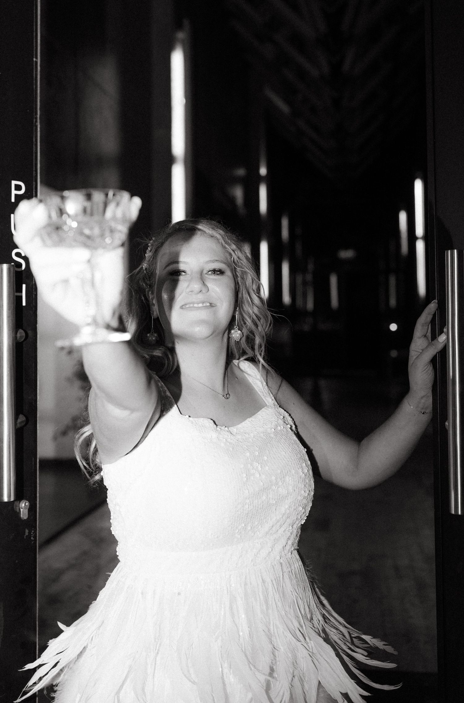 Black and white photo of a bride in a flowing dress posing in dramatic lighting.