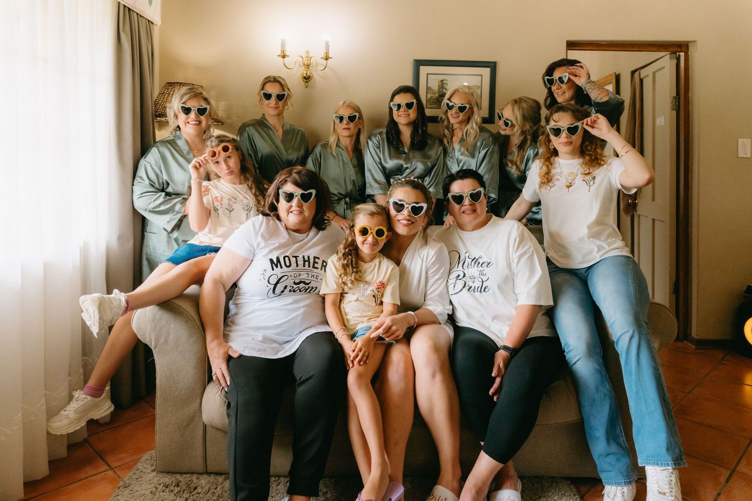 A group of friends lounging together on a couch in matching white t-shirts and casual attire.