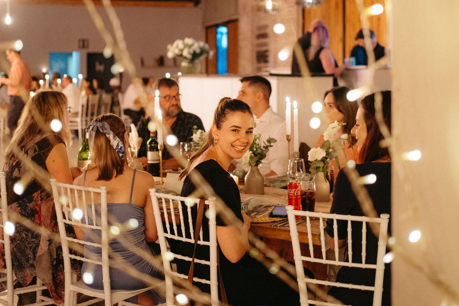 Wedding reception with white chiavari chairs, candlelit tables, and festive lighting creating warm ambiance.